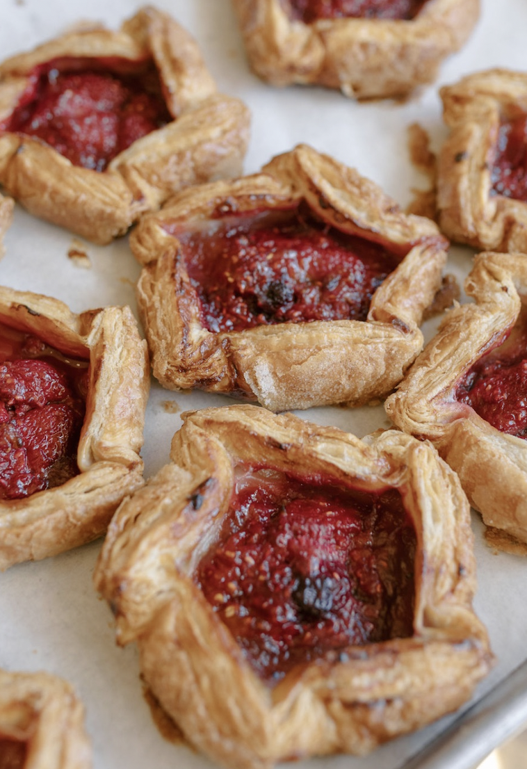 Close-up of strawberry jam Danish pastries on a baking sheet.