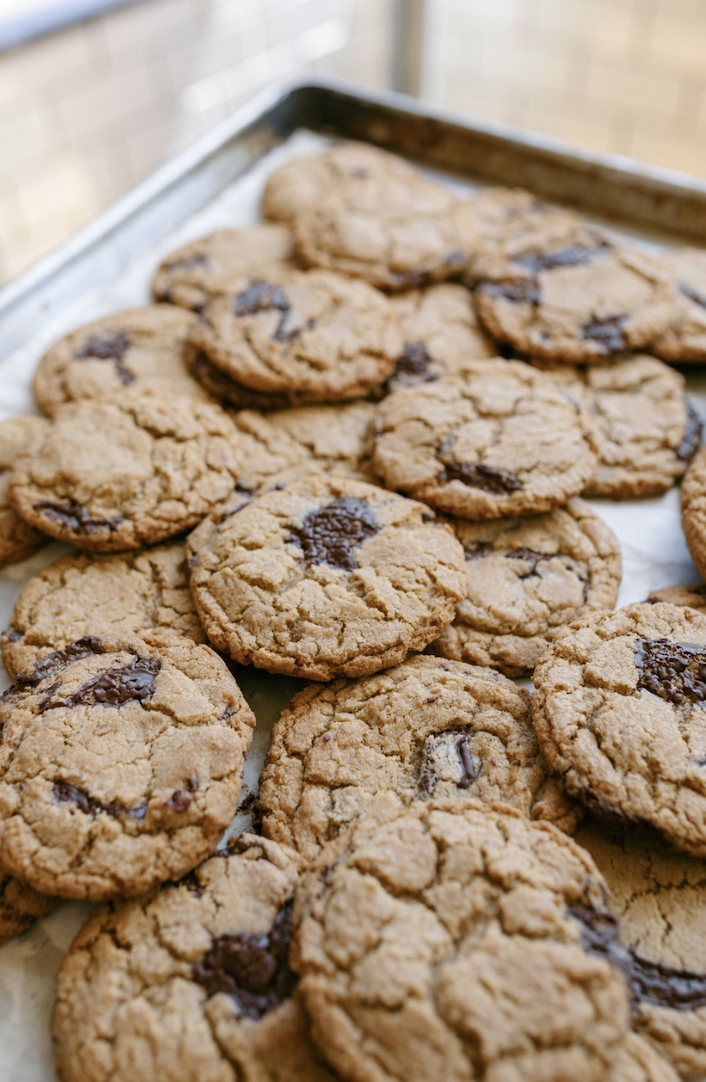 A tray filled with freshly baked chocolate chip cookies on a baking sheet lined with parchment paper.