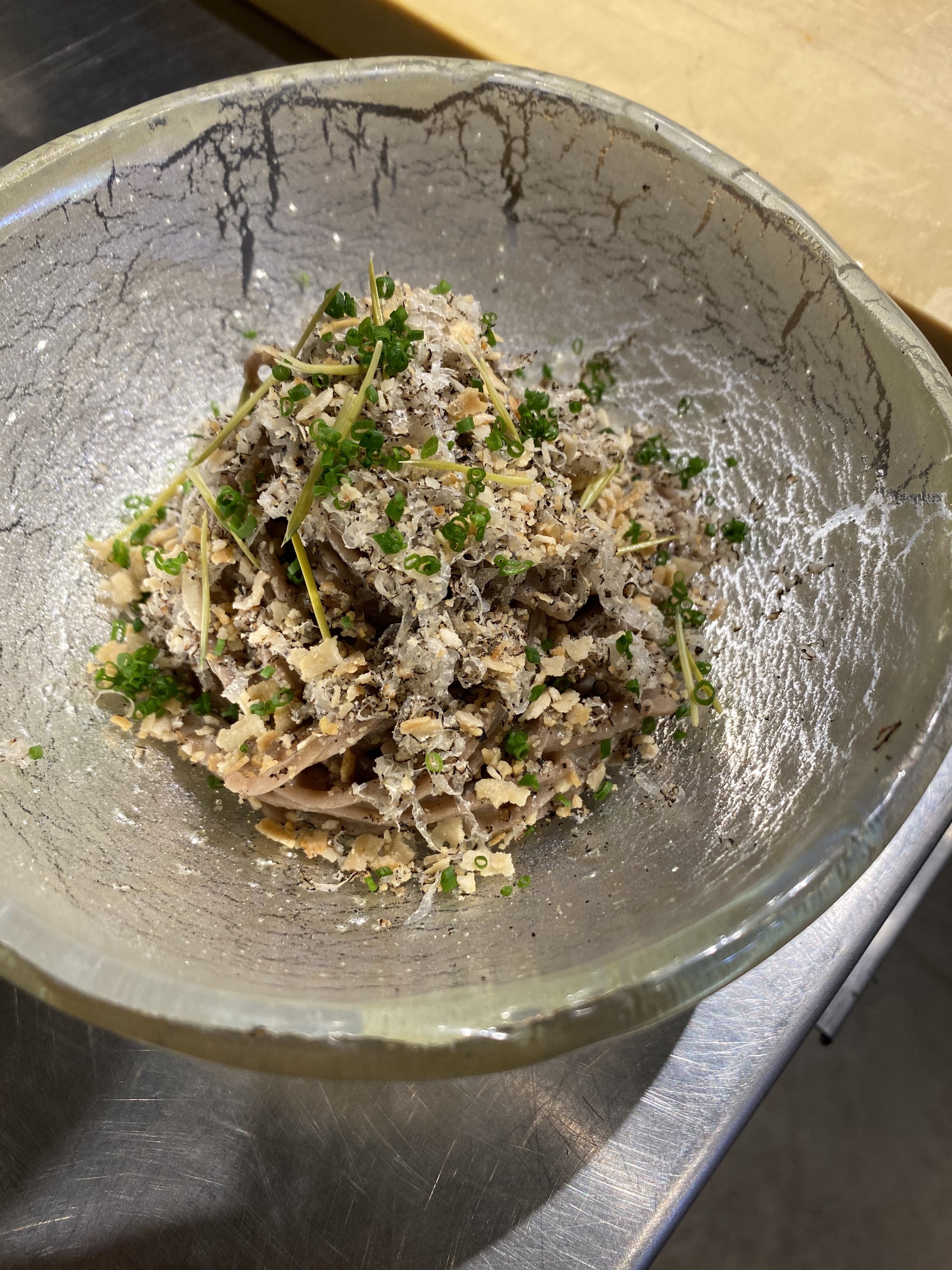 buckwheat noodle seasoned with fresh pressed pine nut oil and pine needle fish sauce, with black truffle jangachi, spruce tips