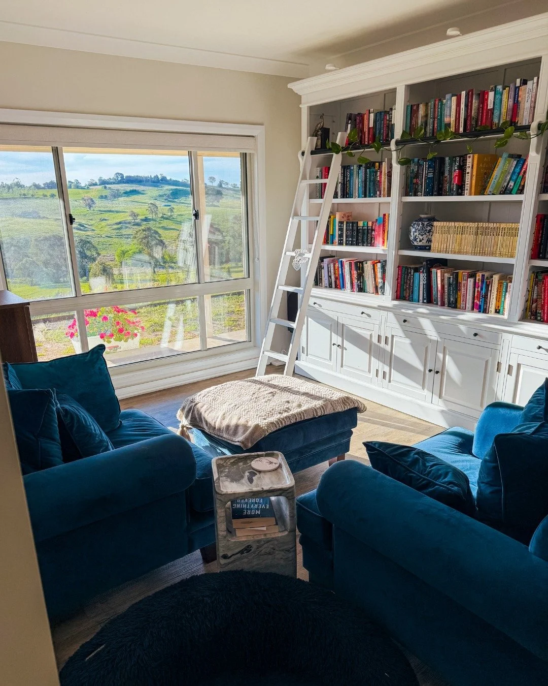 This little corner of my home might just be my favourite place in the world. 📚💛

Tall shelves filled with stories, a comfy chair to disappear into them, and a view of green hills that somehow makes reading feel even more magical.

It&rsquo;s where 