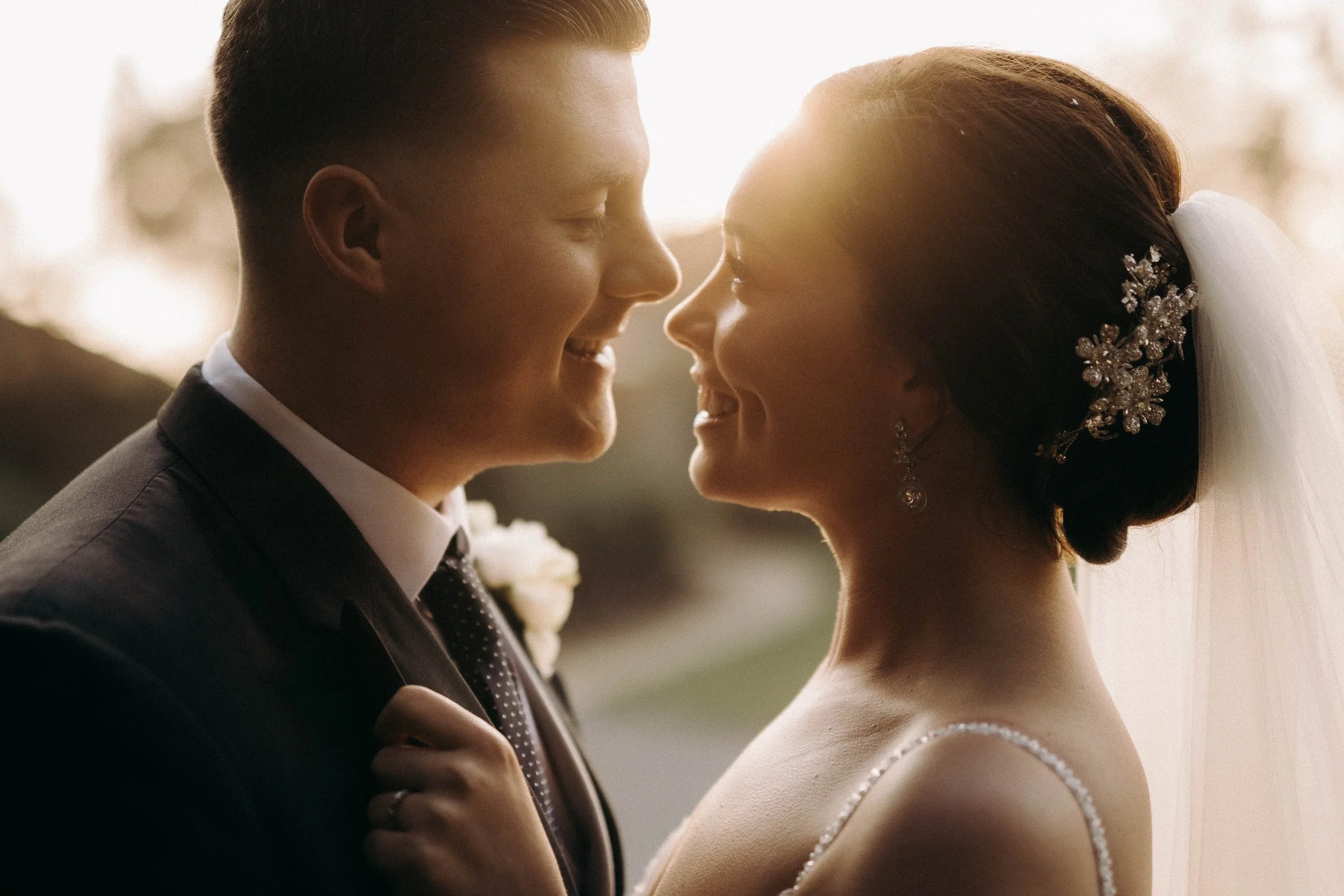 Close-up of a bride and groom at Mythe Barn sharing an intimate moment at sunset, with warm golden light illuminating their faces.