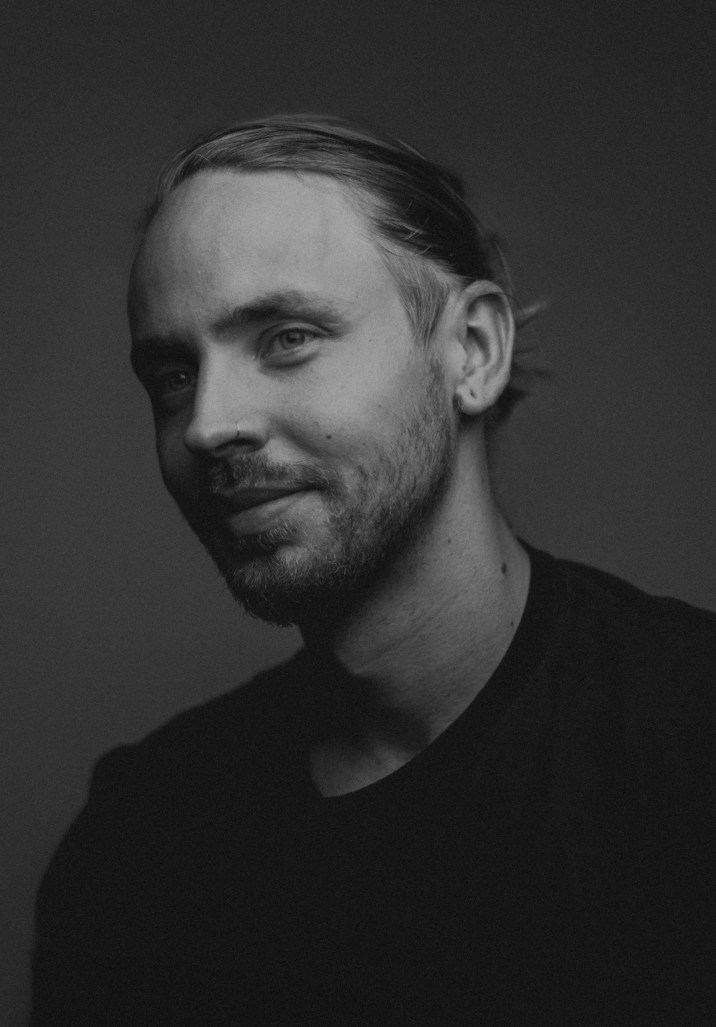 Black and white portrait of a man with short hair and a beard, facing left.