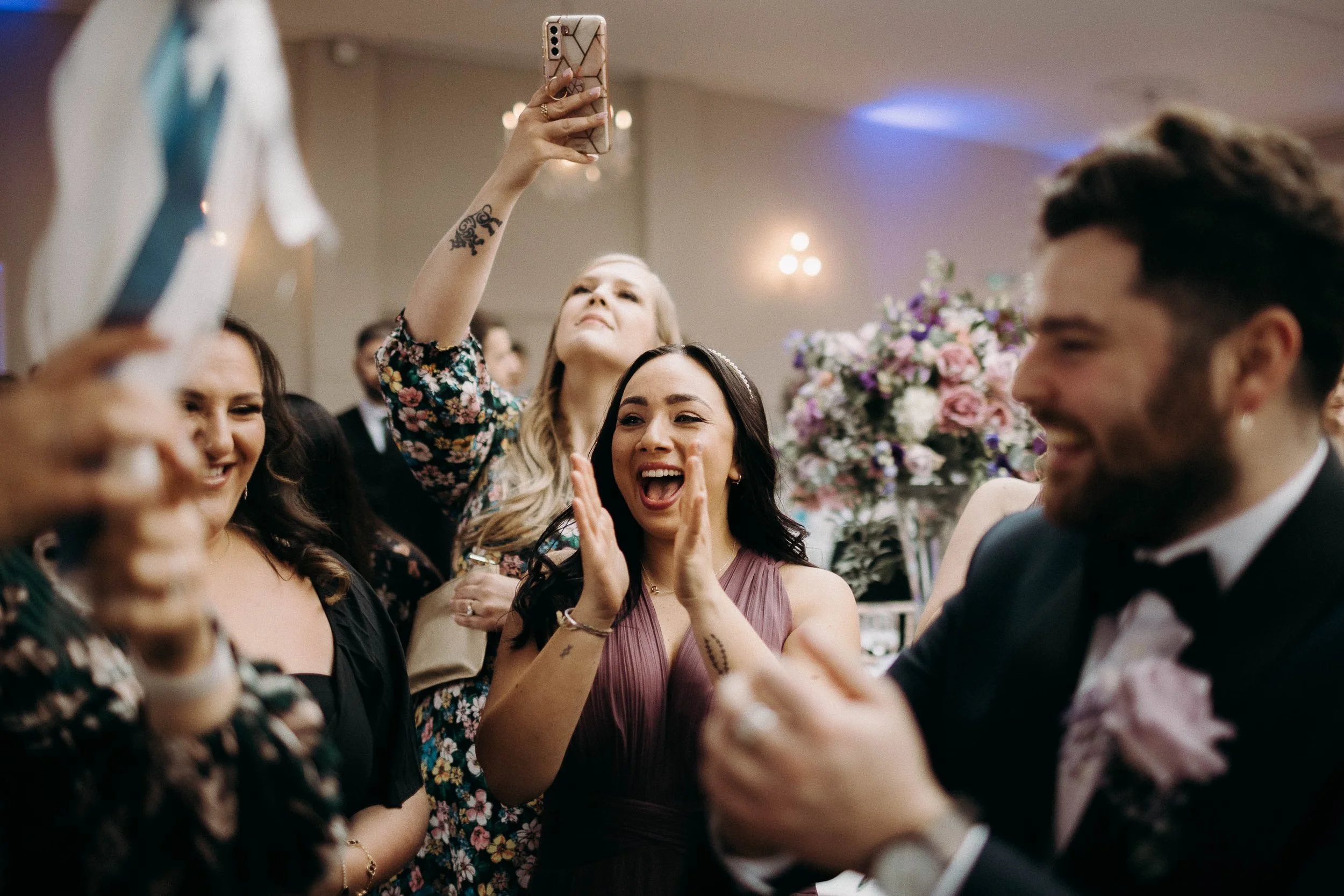 Wedding guests cheering, clapping and filming during the evening celebrations at the reception.