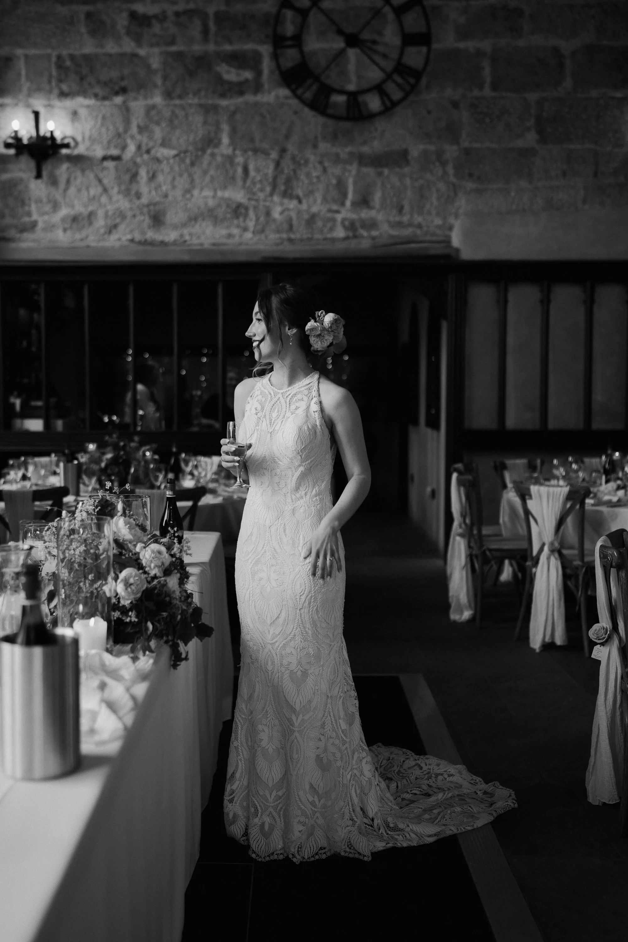 Bride holding a champagne glass and smiling inside the reception room at The Priest’s House in Skipton.