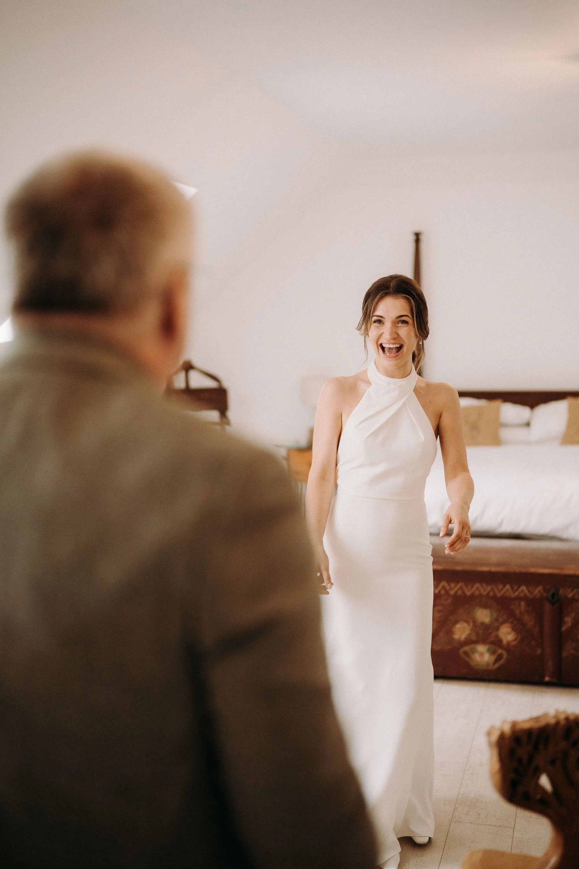 Bride smiling excitedly as her dad sees her in her wedding dress for the first time in the bridal suite at Two Woods Estate.