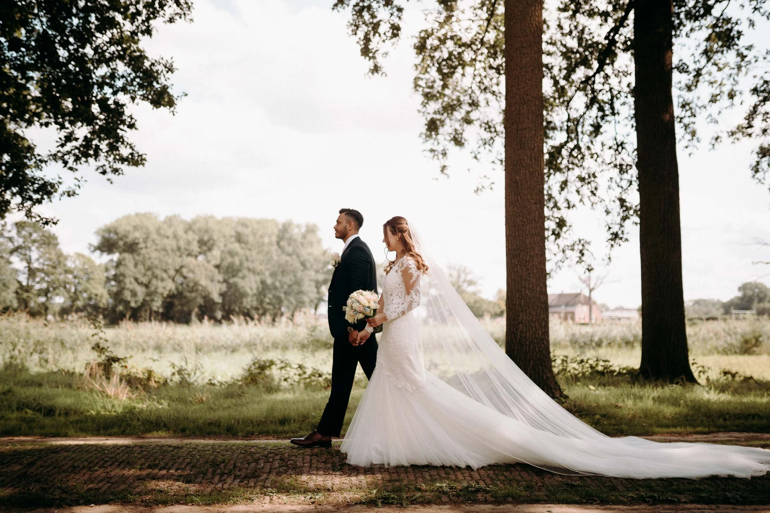 Bride and groom walking through the parkland together at Kasteel Heeswijk.