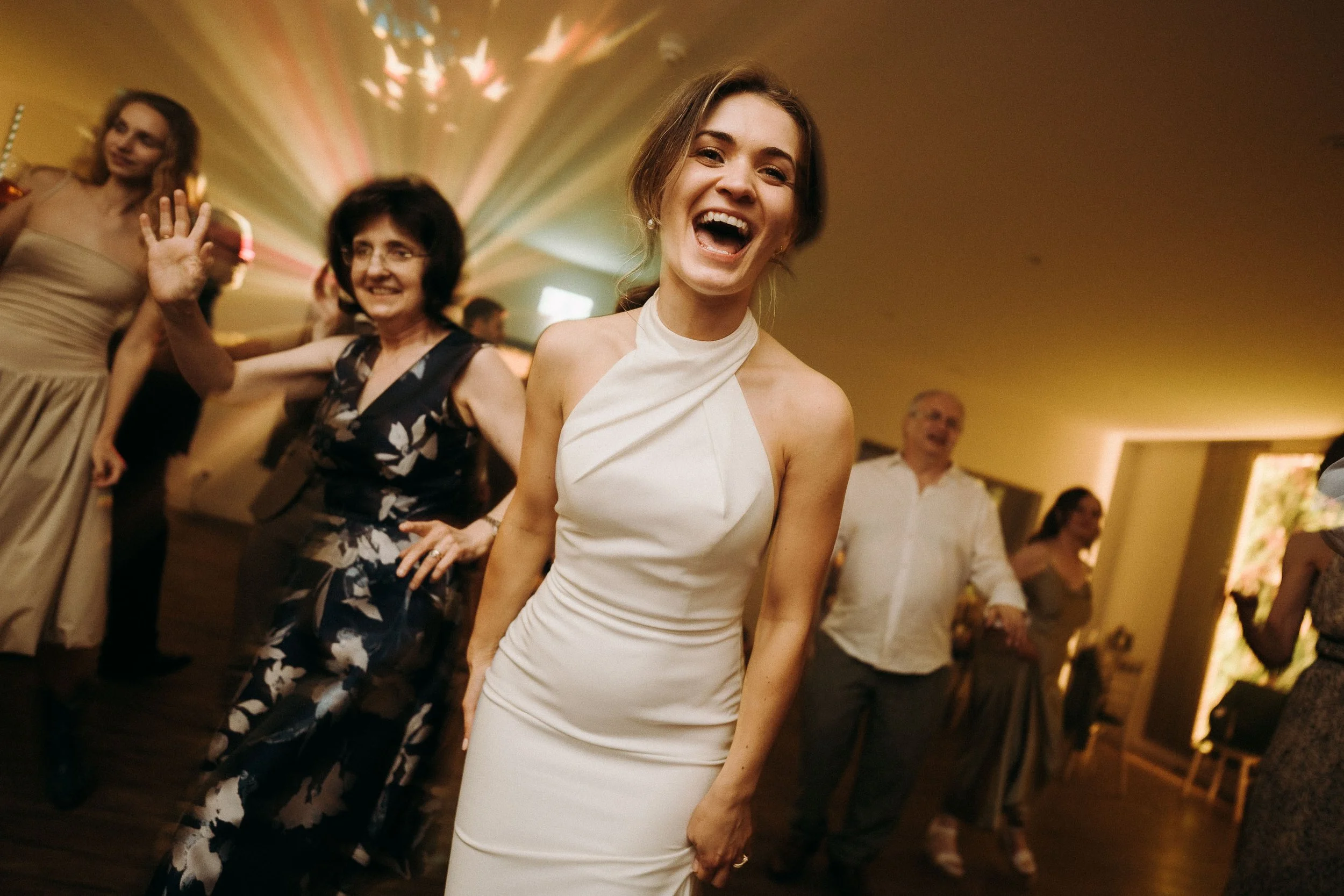 Bride laughing and dancing with guests during the late-night wedding celebration at Two Woods Estate.