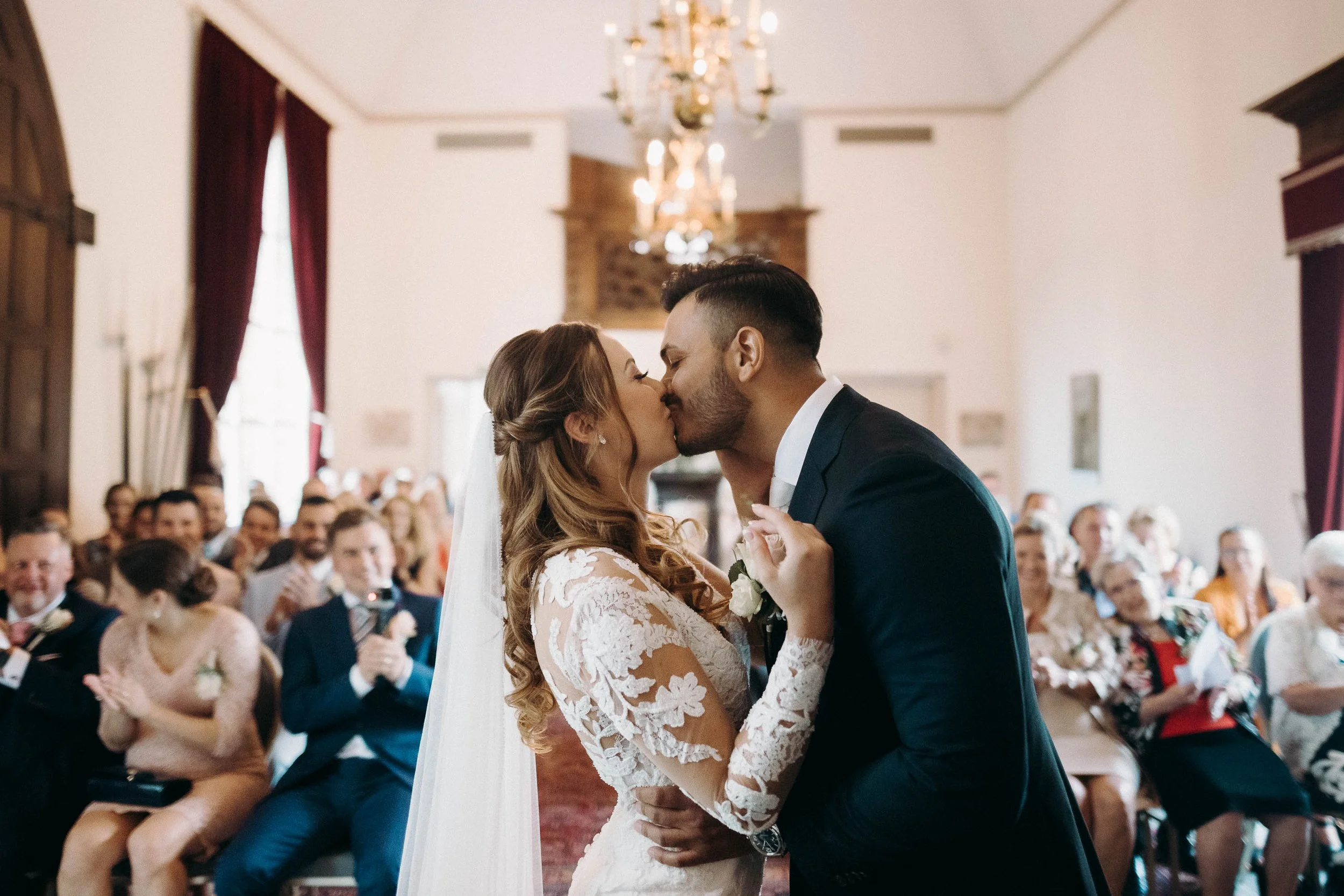 Dutch bride and groom share their first kiss at the end of the ceremony as guests applaud at Kasteel Heeswijk.