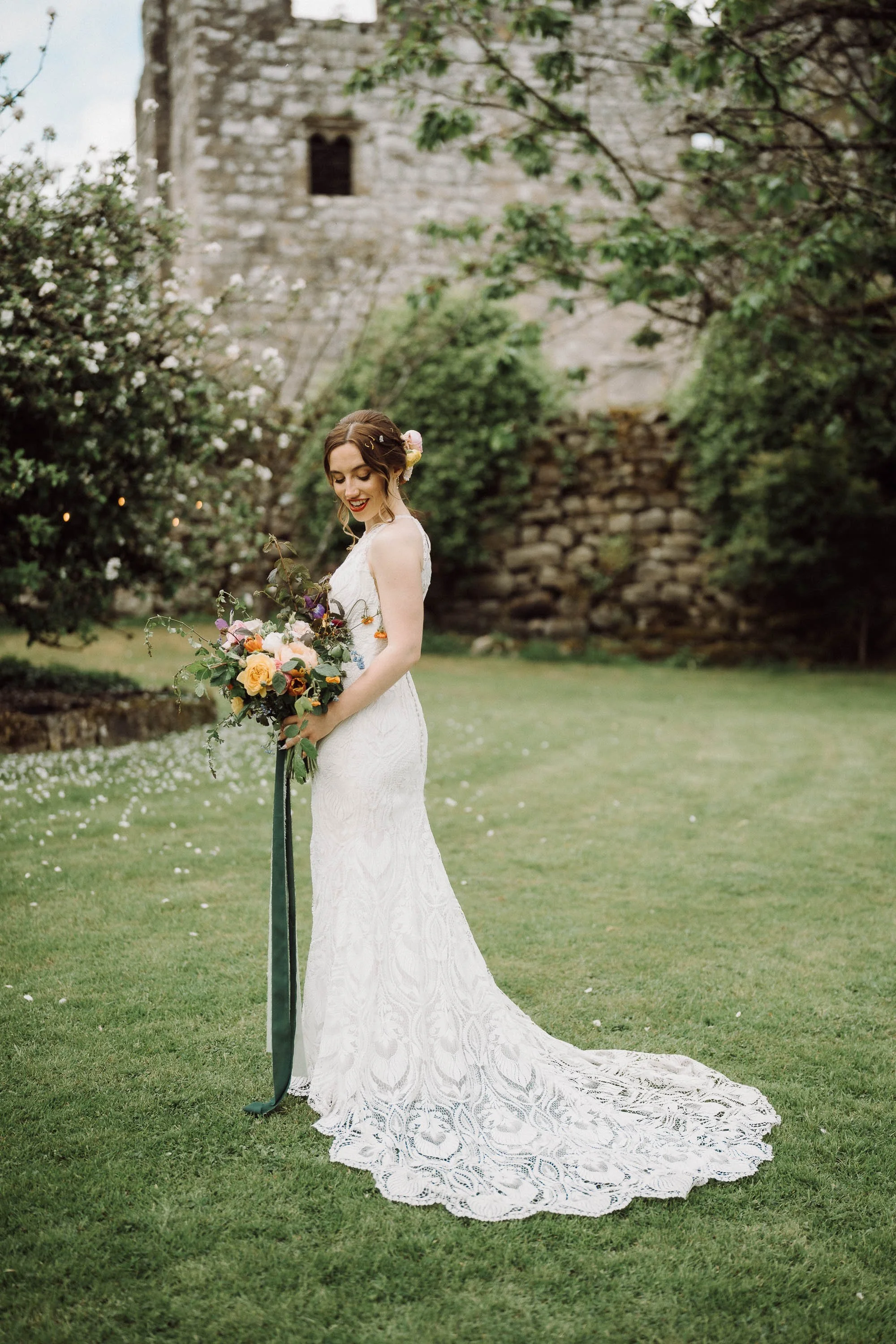 Bride holding her colourful bouquet and smiling in the garden outside The Priest’s House in Skipton.