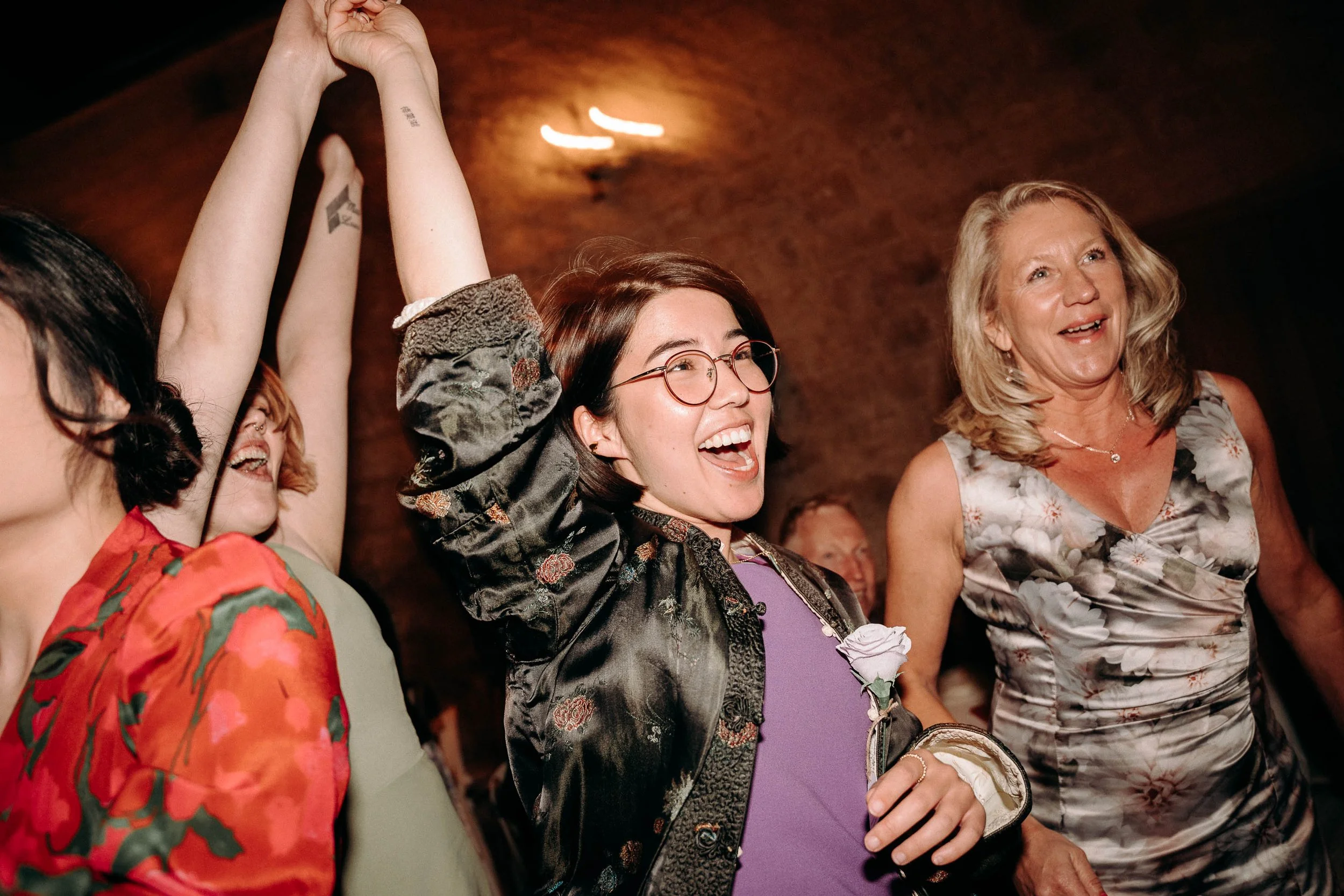 Asian lady in floral jacket dances with other wedding guest during the reception at The Priests House in Skipton shot with shutter drag.