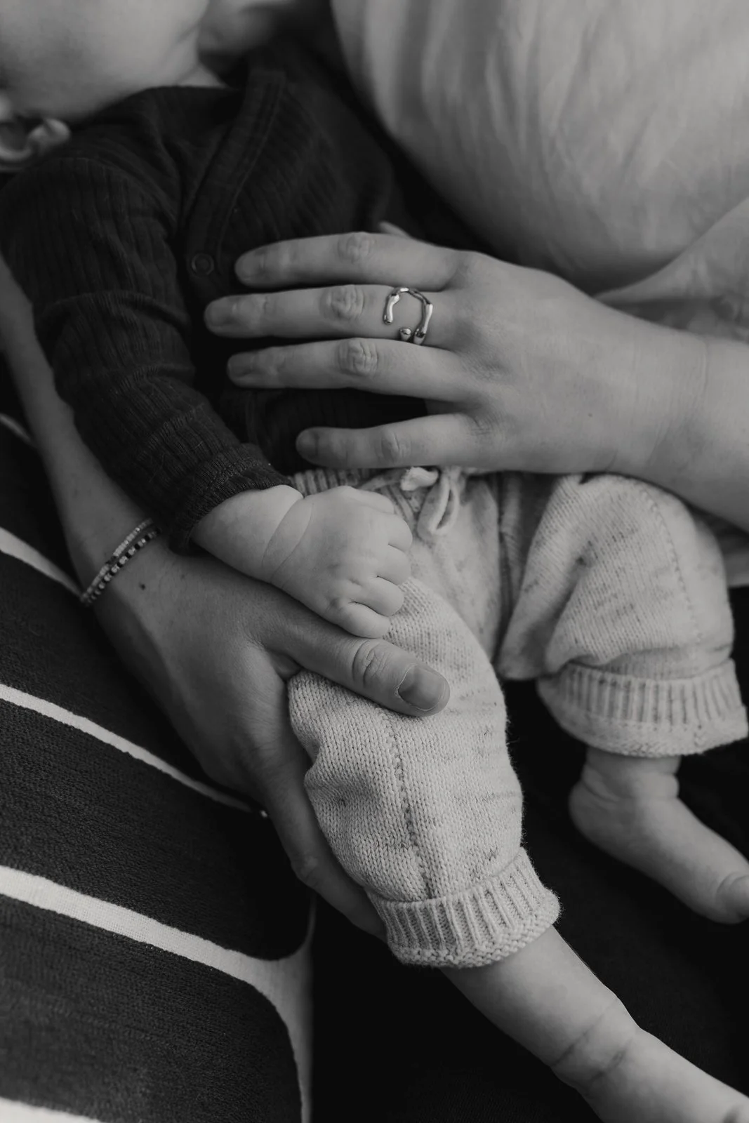 Gezicht van een baby die in de armen van een vrouw ligt terwijl een man haar neus zachtje raakt. Vrouw en man kijken naar de baby, die verbaasd kijkt.