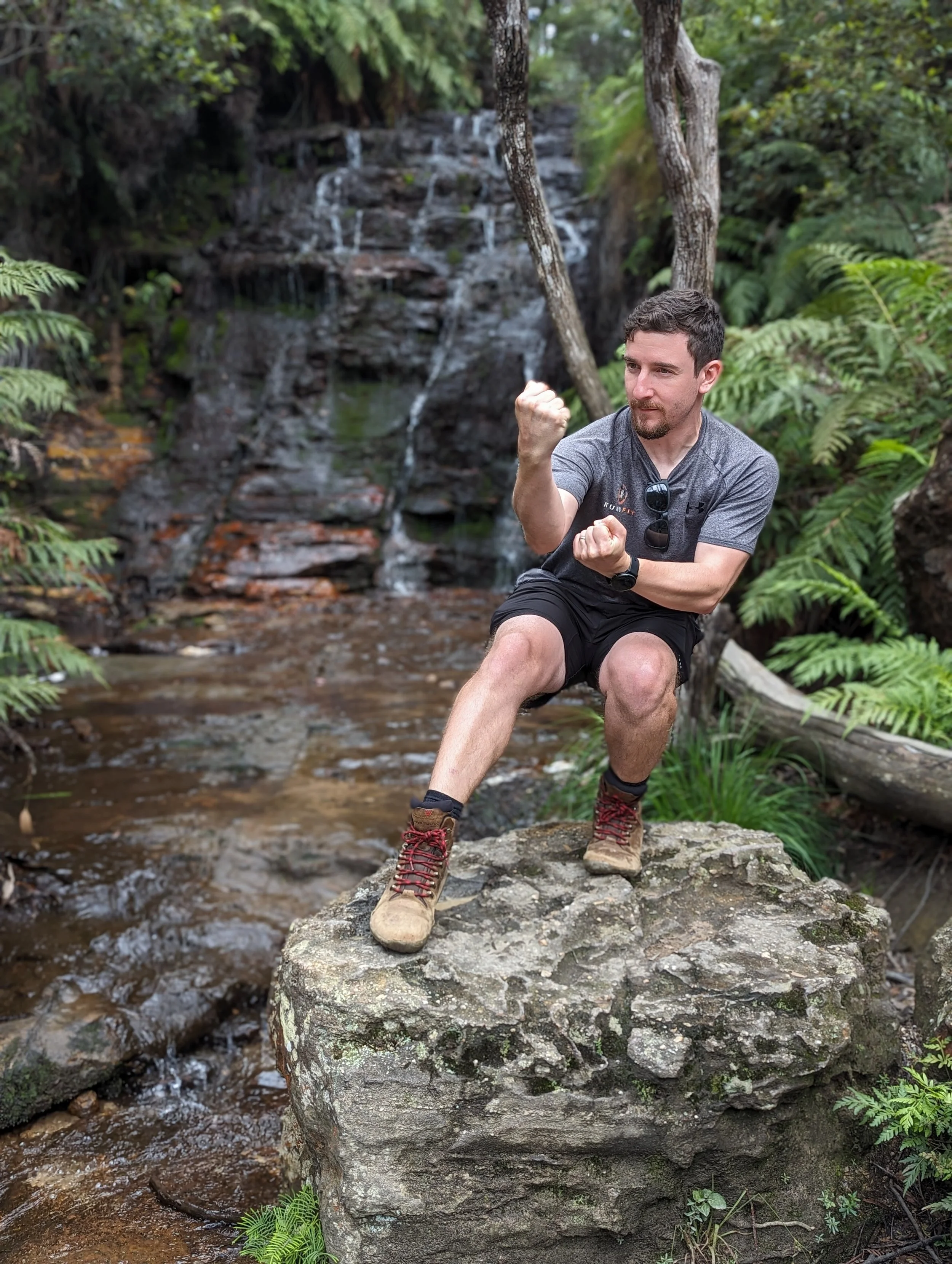 Damien standing in xu bu in front of a waterfall