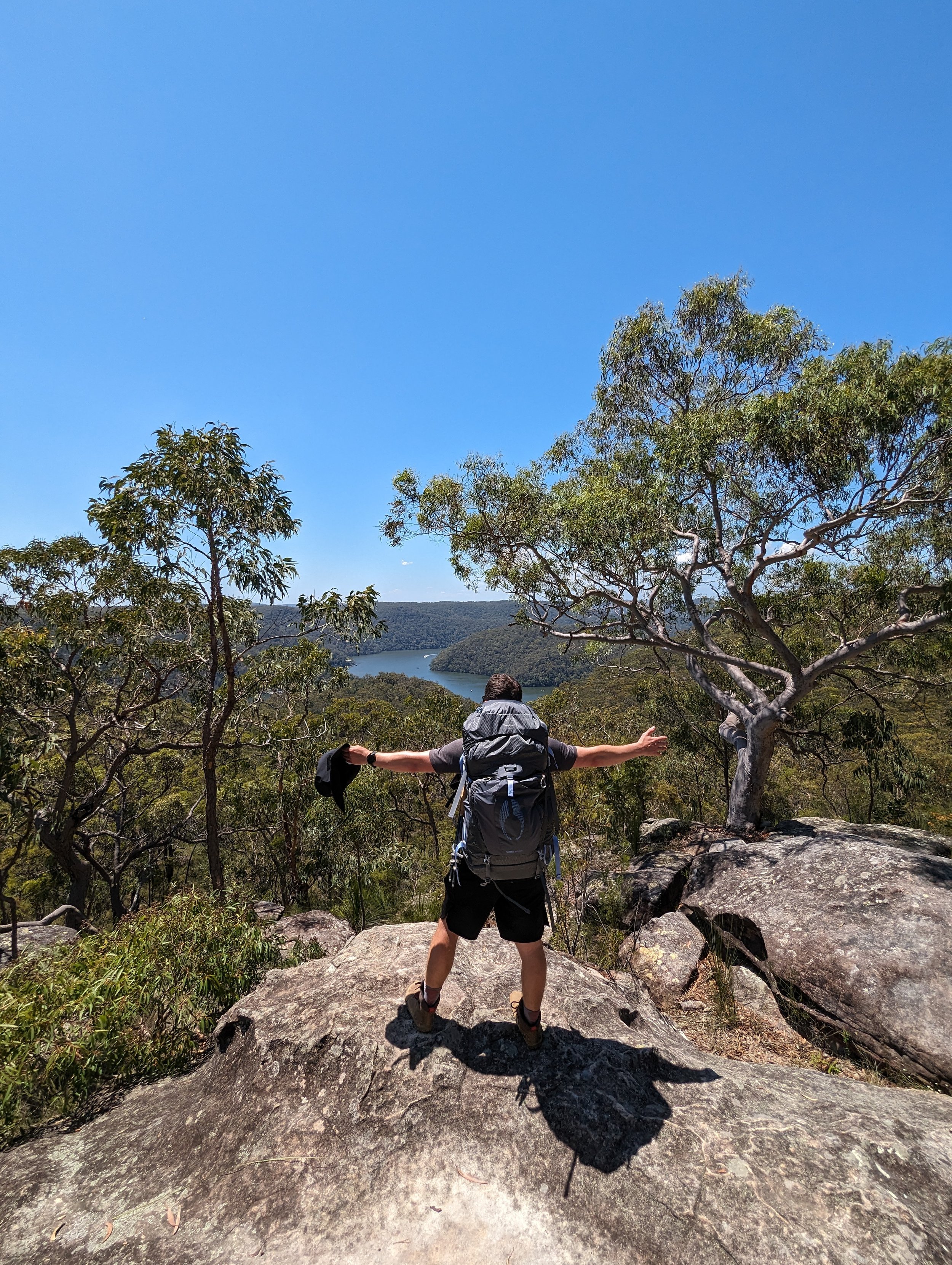 Damien standing on a rocky outcrop in the Blue Mountains, New South Wales with a laden hiking pack