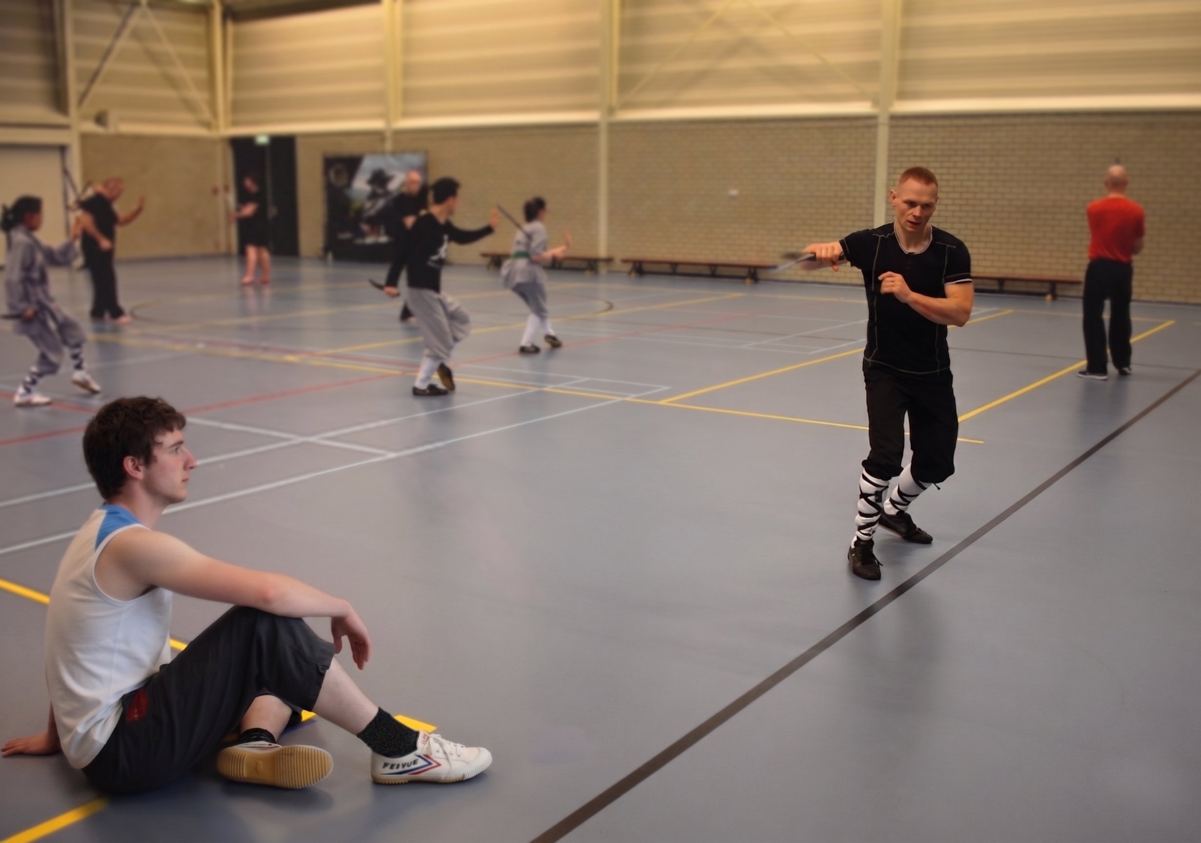 Damien watching on as others carry on training kung fu and he sits out on the rest of the session