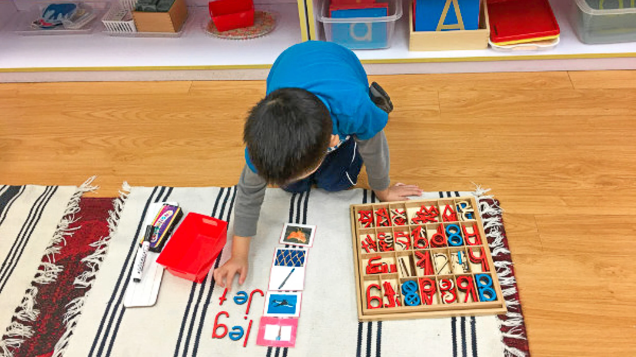 Child playing with educational toys and blocks on a table in a classroom setting.