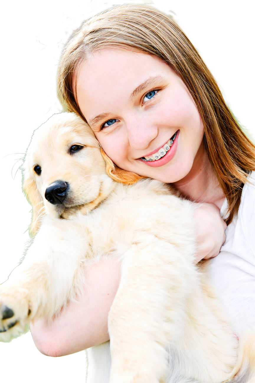 A girl smiling and hugging a golden retriever puppy.