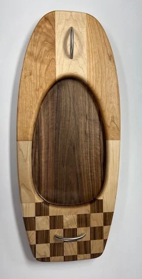 A piece of woodworking by Dr. Kuhlberg, a custom charcuterie board in the form of a freestyle kayak