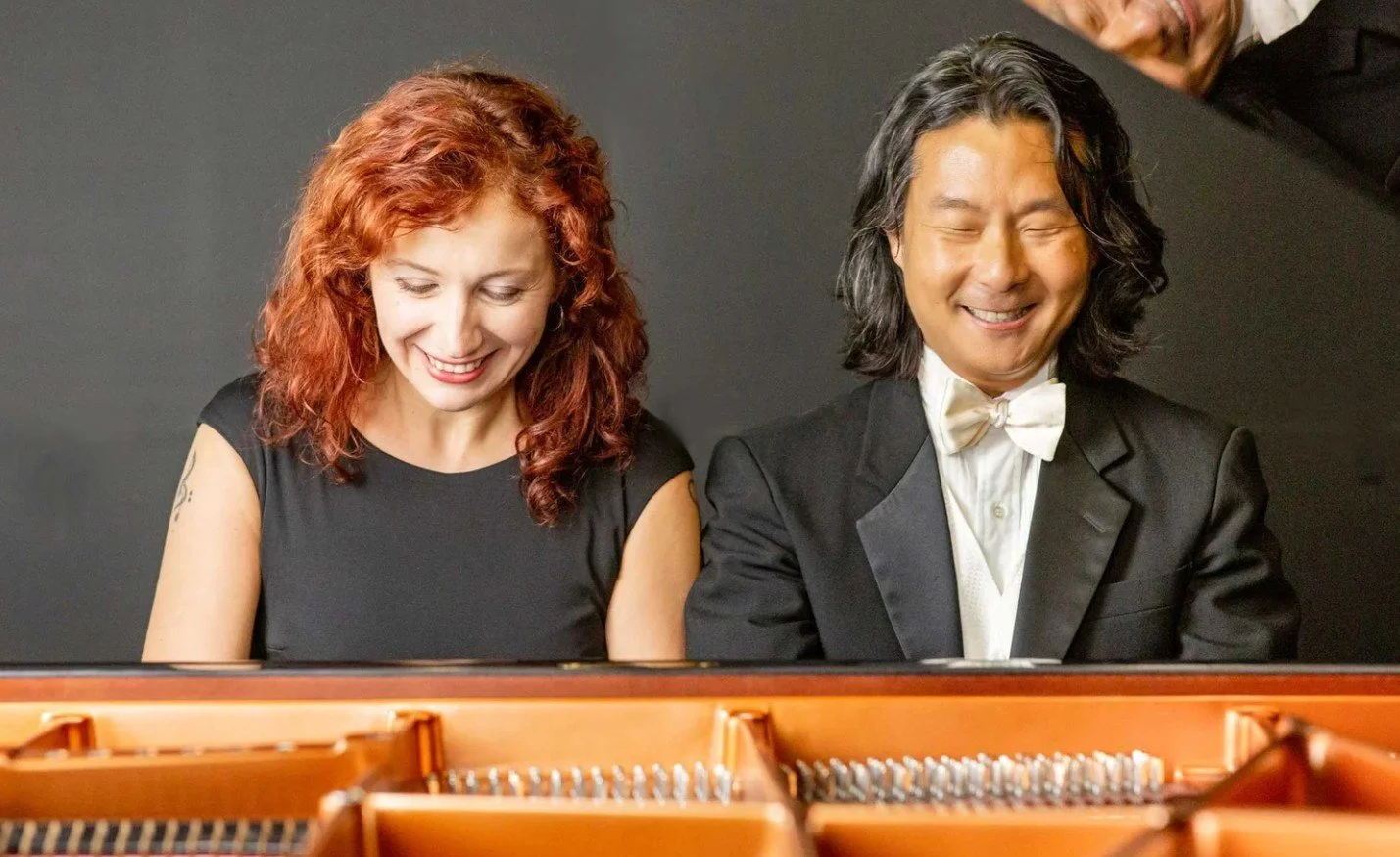 2 people sitting at a piano