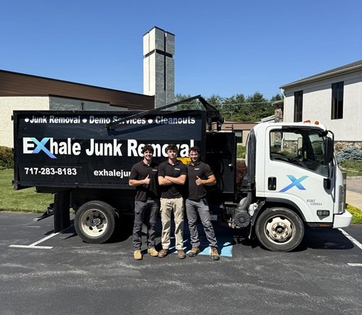 Three men standing in front of a exhale junk removal truck