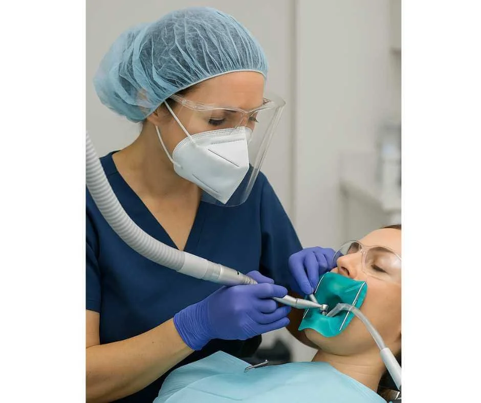 Biological dentist performing safe mercury amalgam filling removal using SMART protocol with protective equipment and oxygen support
