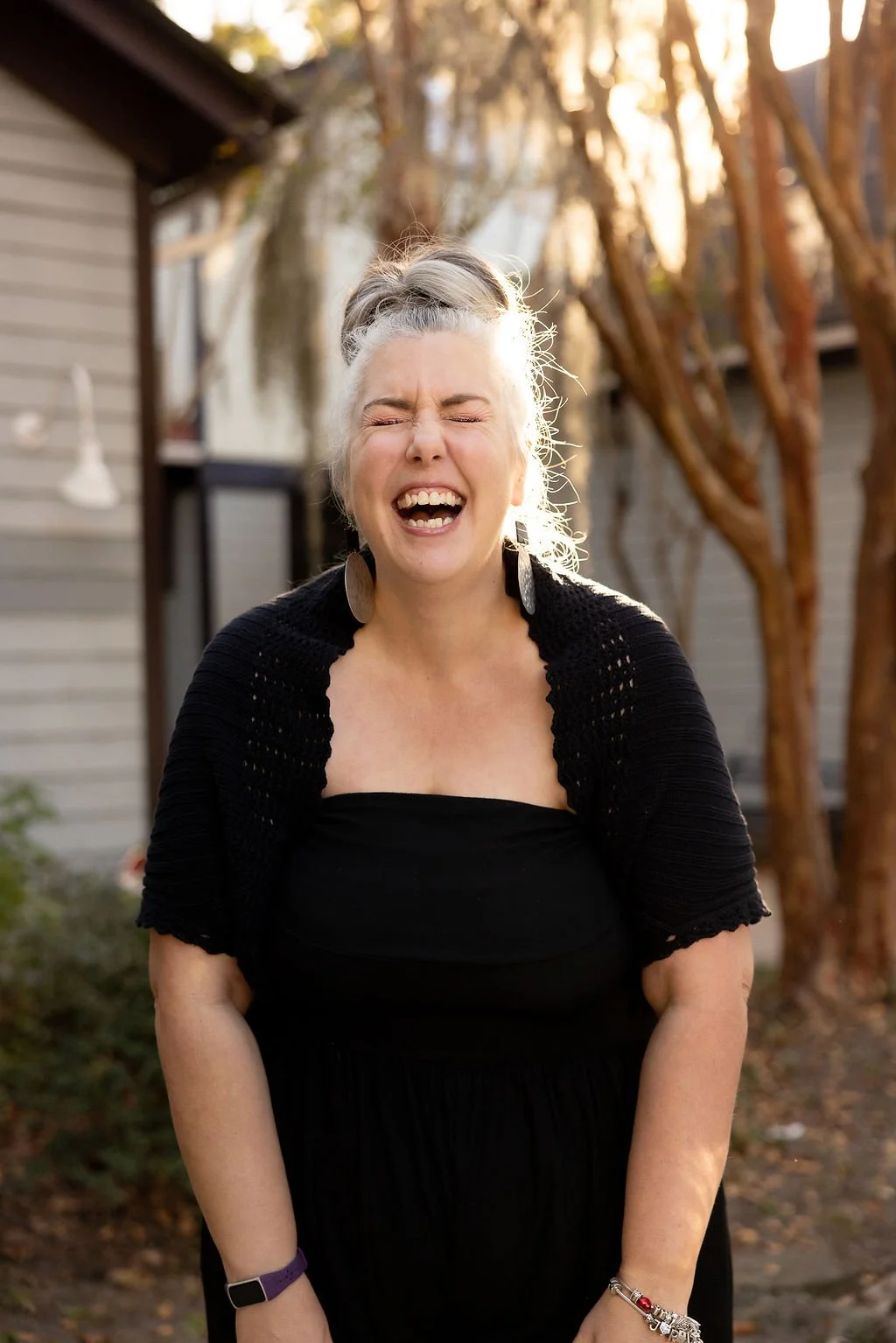 Joslin Romphf Dennis, voice teacher and owner of JRD Voice Studio, laughing joyfully outdoors in the sunlight