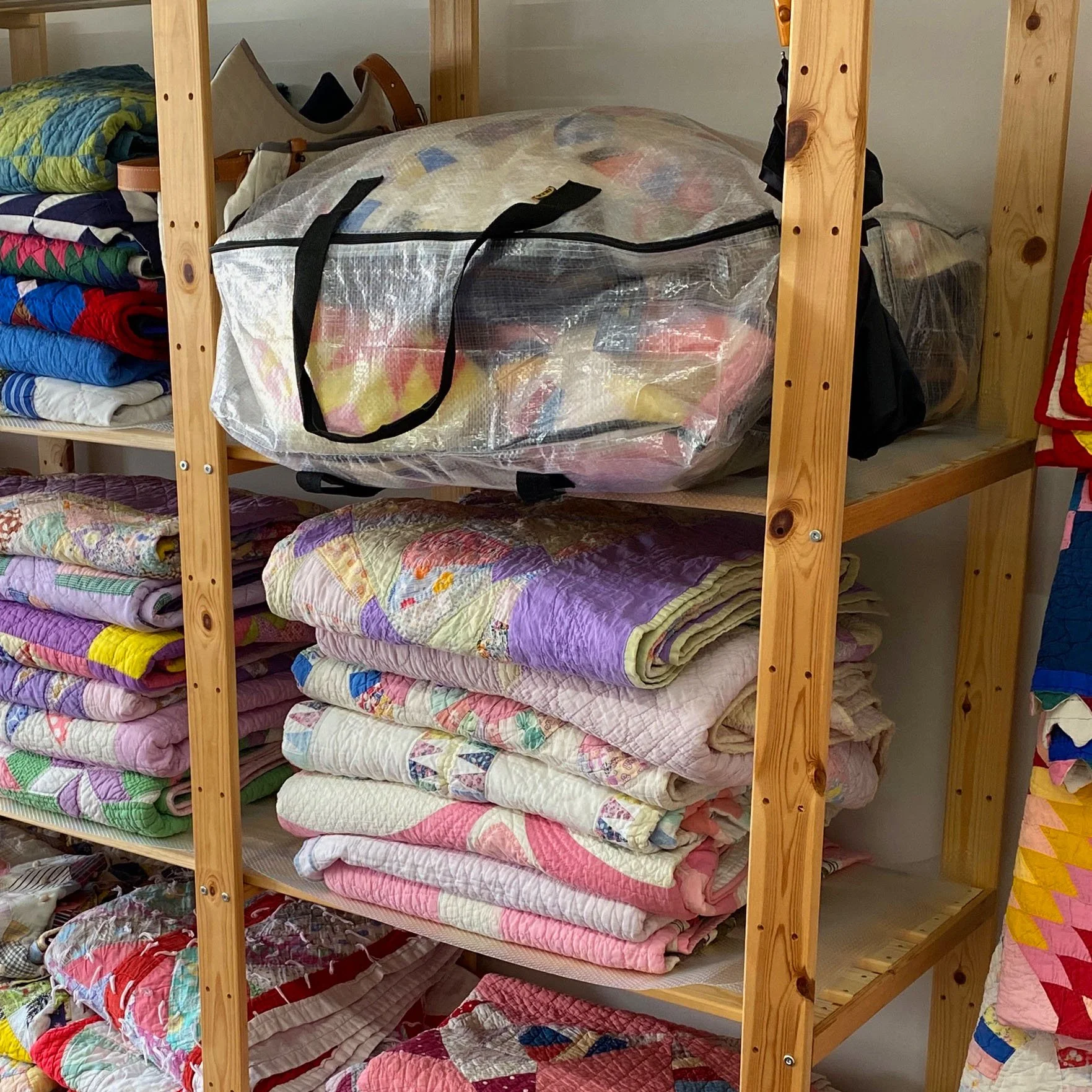 Wooden bunk bed with folded quilts and blankets on each shelf, colorful quilt patterns visible on the pillows and blankets.