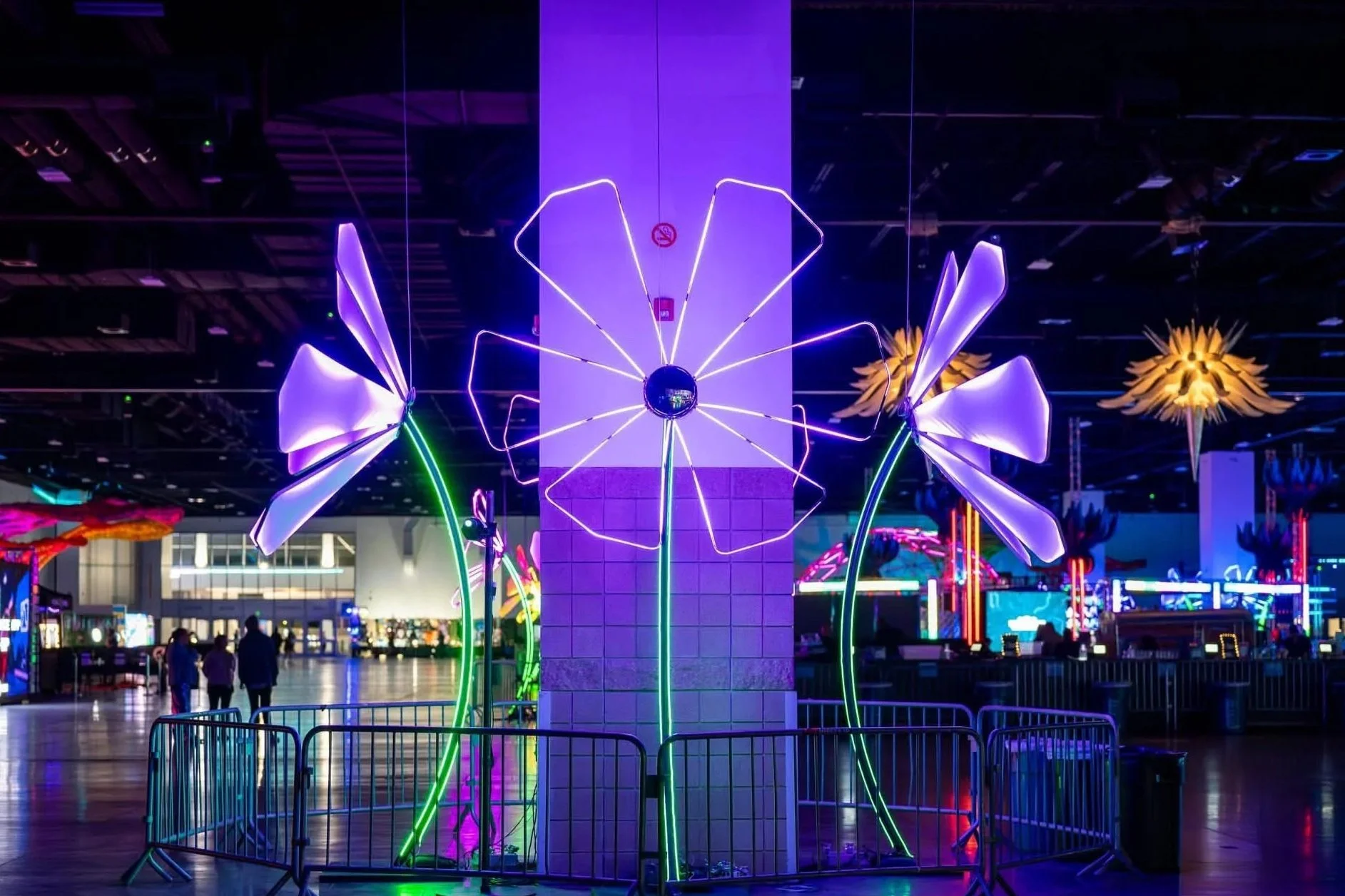 Colorful LED neon flower sculptures with illuminated petals and stems within an indoor music festival