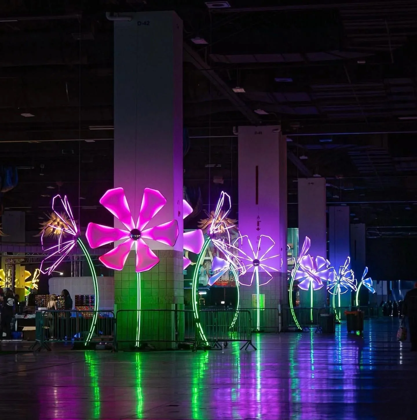 Colorful LED-lit flower decorations inside a dark indoor space.