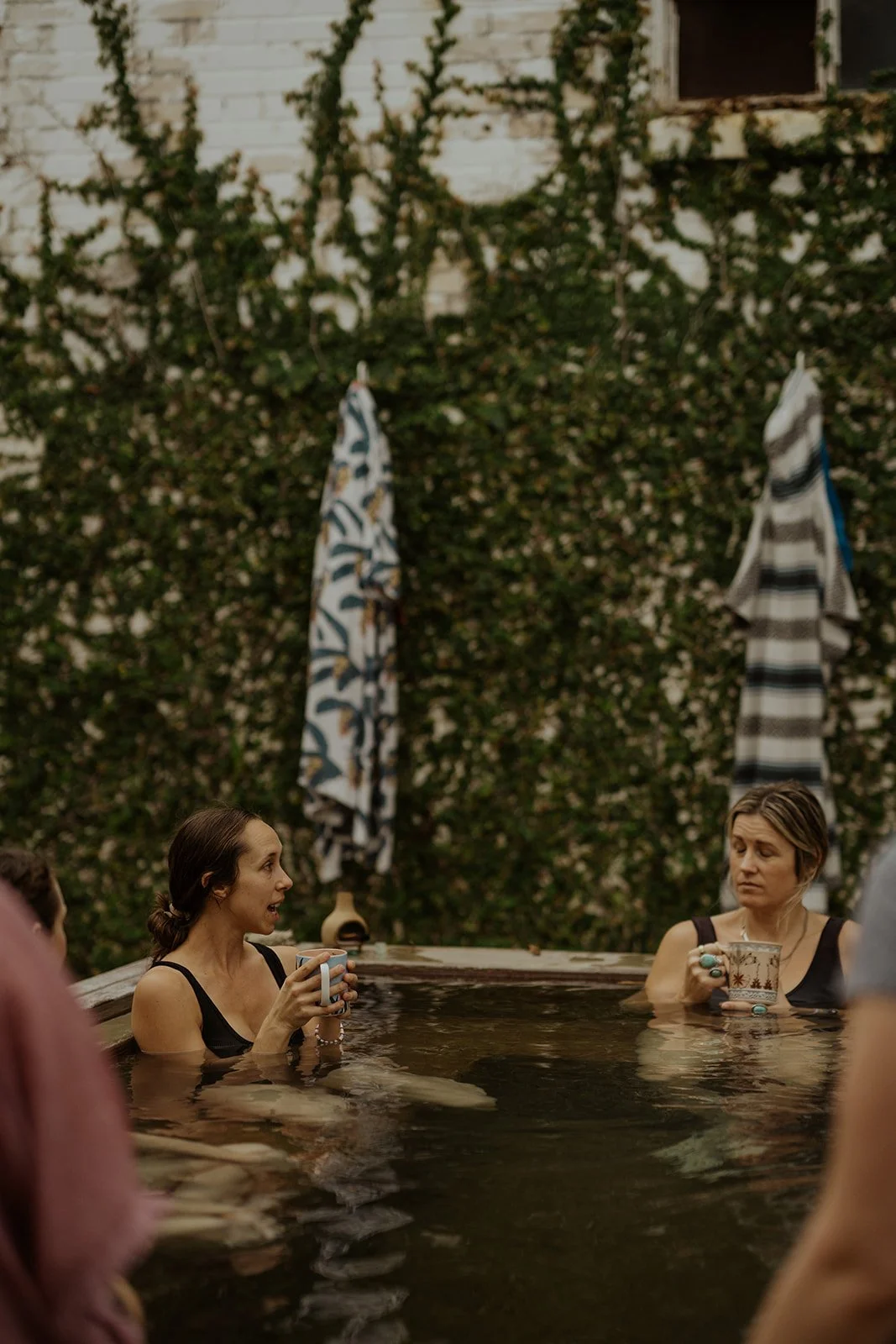 Natalie Forster and a Revived Roots Collective member relaxing in natural hot springs during a wellness retreat experience focused on connection, restoration, and holistic health.