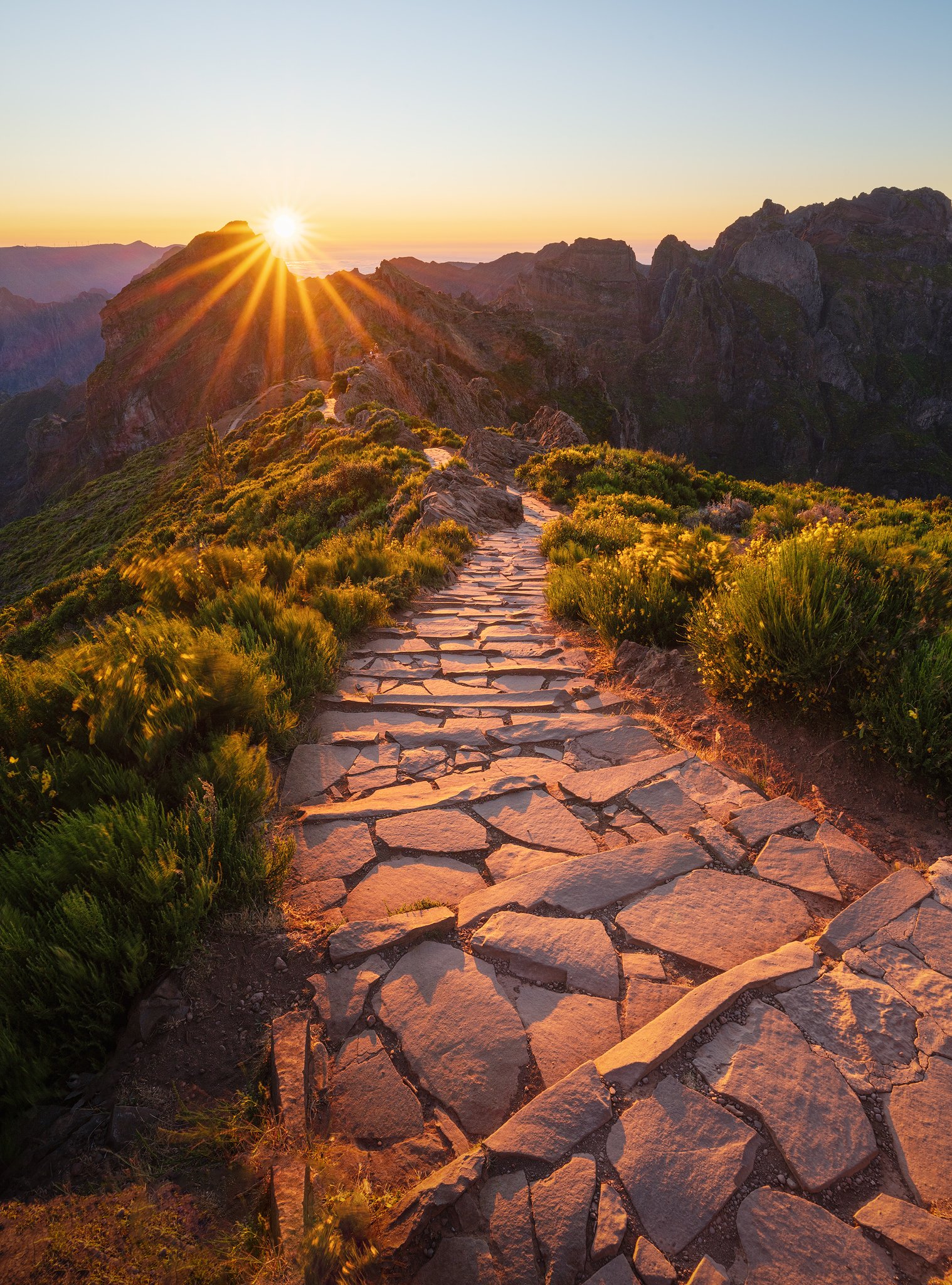 Stone path along a mountain ridge in Madeira with the sun as a defined star at sunrise