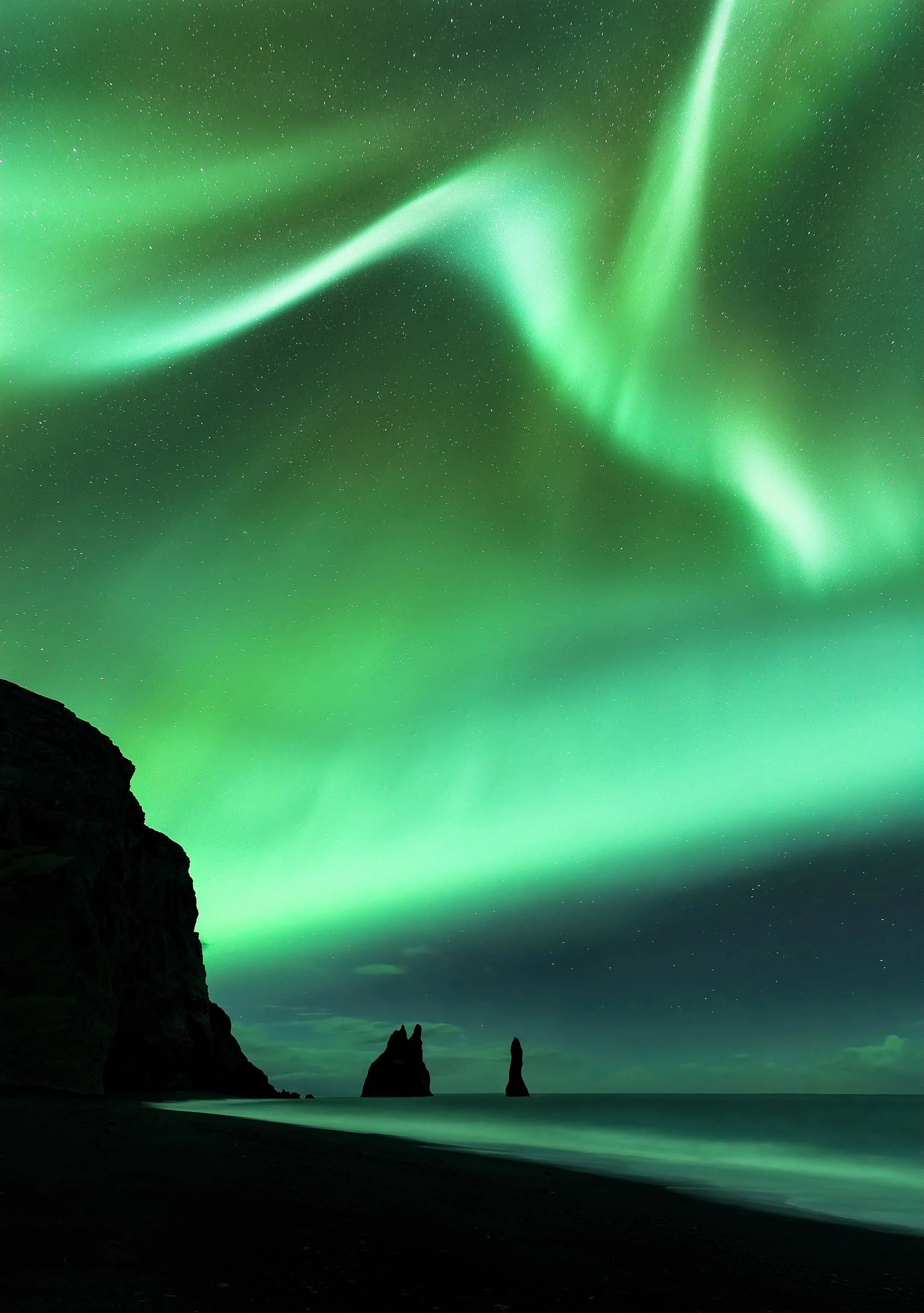 Aurora corona exploding above the Reynisdrangar sea stacks at Reynisfjara beach, Iceland. foreground at ISO 1600, f/4, 30 seconds; aurora at ISO 4000, f/2.8, 2 seconds