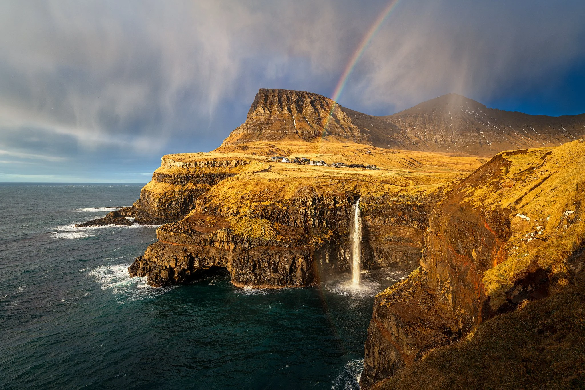 Rainbow over Múlafossur waterfall and Gásadalur village on the cliffs, Faroe Islands