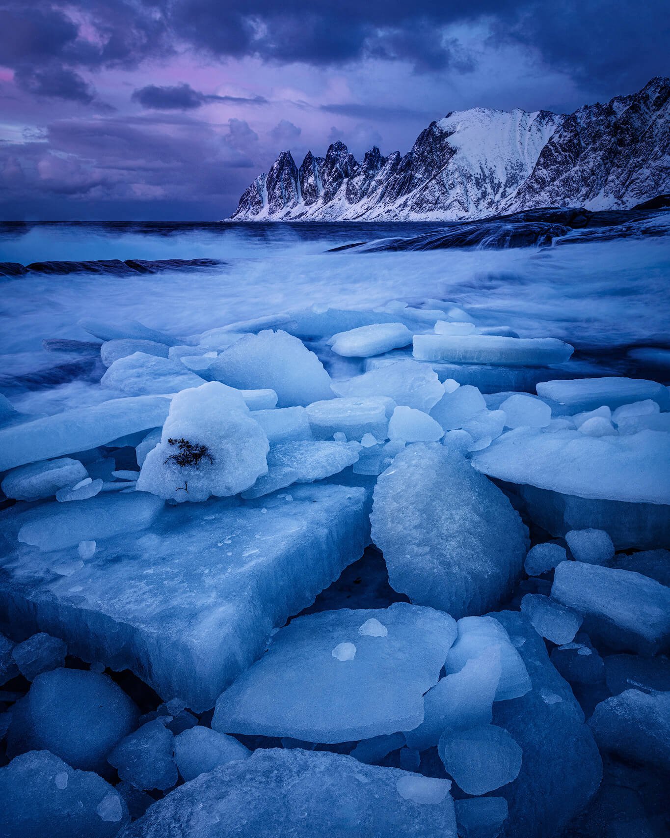 We’re at Tungeneset on Senja Island in northern Norway, where winter sea ice gathers along the shoreline beneath razor-sharp mountains. The cool blue-hour tones and dramatic cloud layers give the scene a raw Arctic feel. It’s an ideal spot for long e