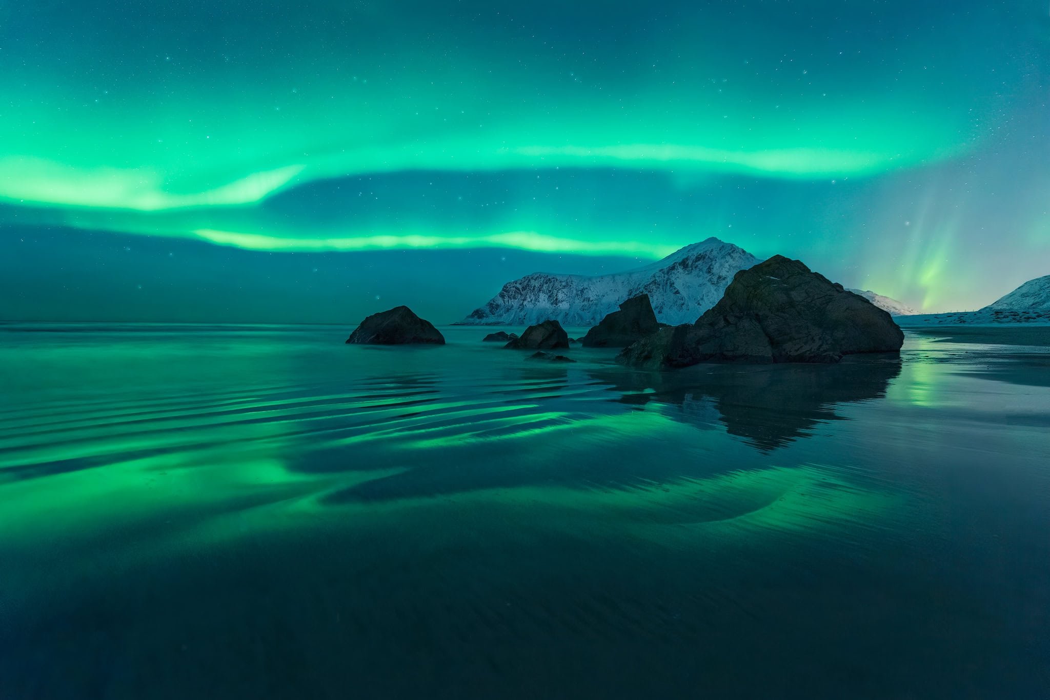 The northern lights aka Aurora borealis reflecting on the wet sands of Skagsanden beach on Lofoten islands in northern Norway