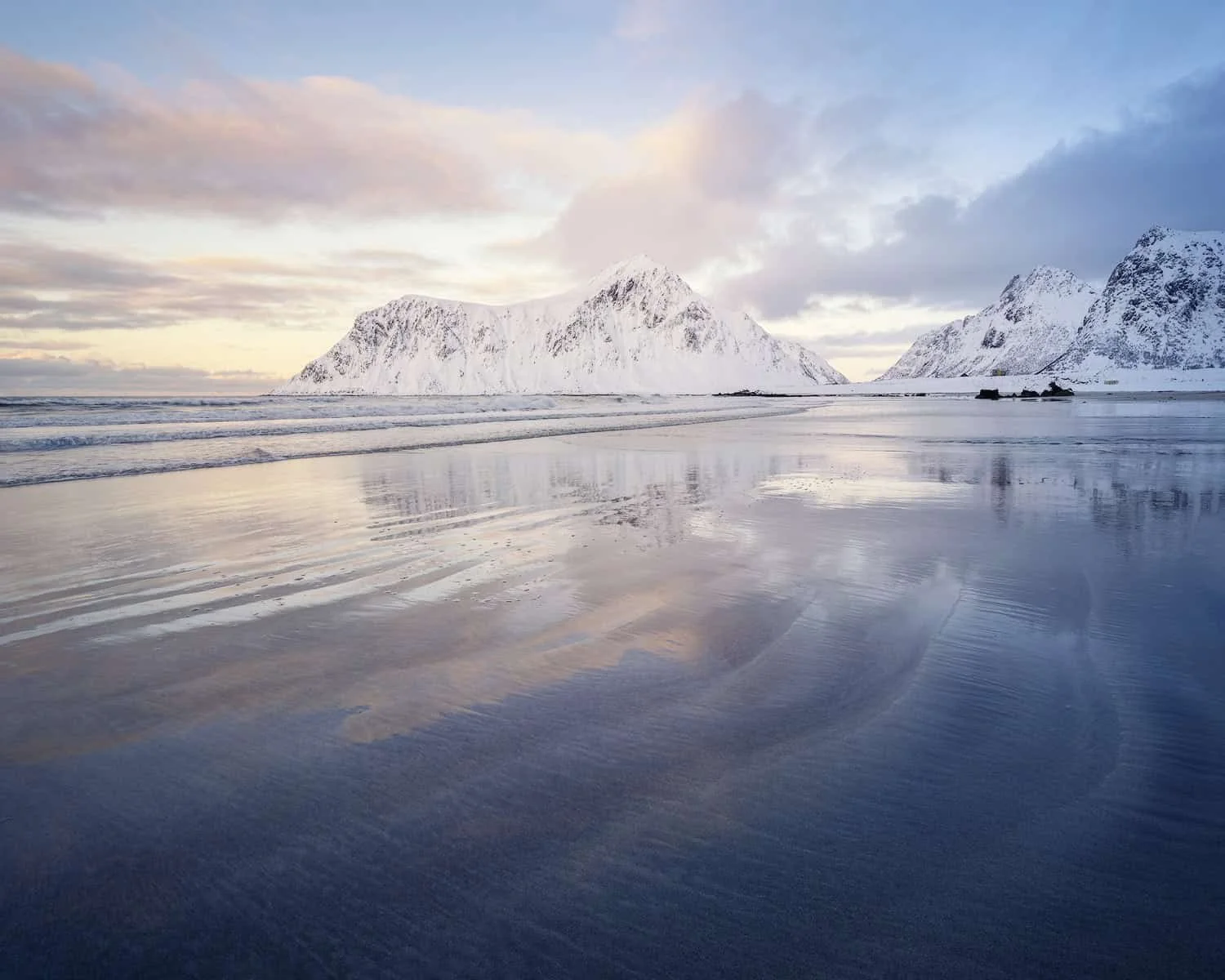 Shoreline curves and mountain reflections at Skagsanden Beach in winter, Lofoten, Norway