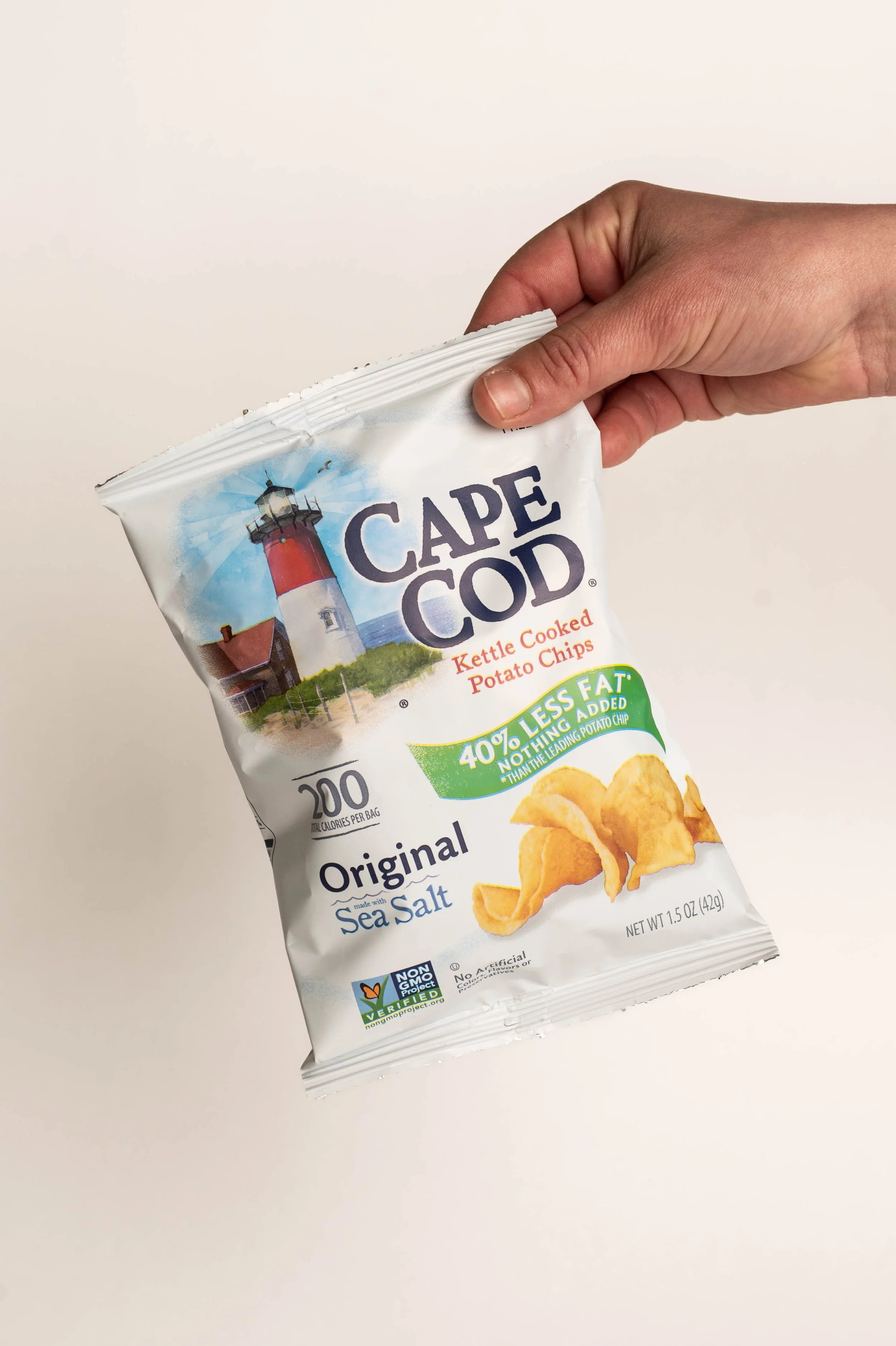 A hand holding a bag of Cape Cod Original Sea Salt kettle cooked potato chips.