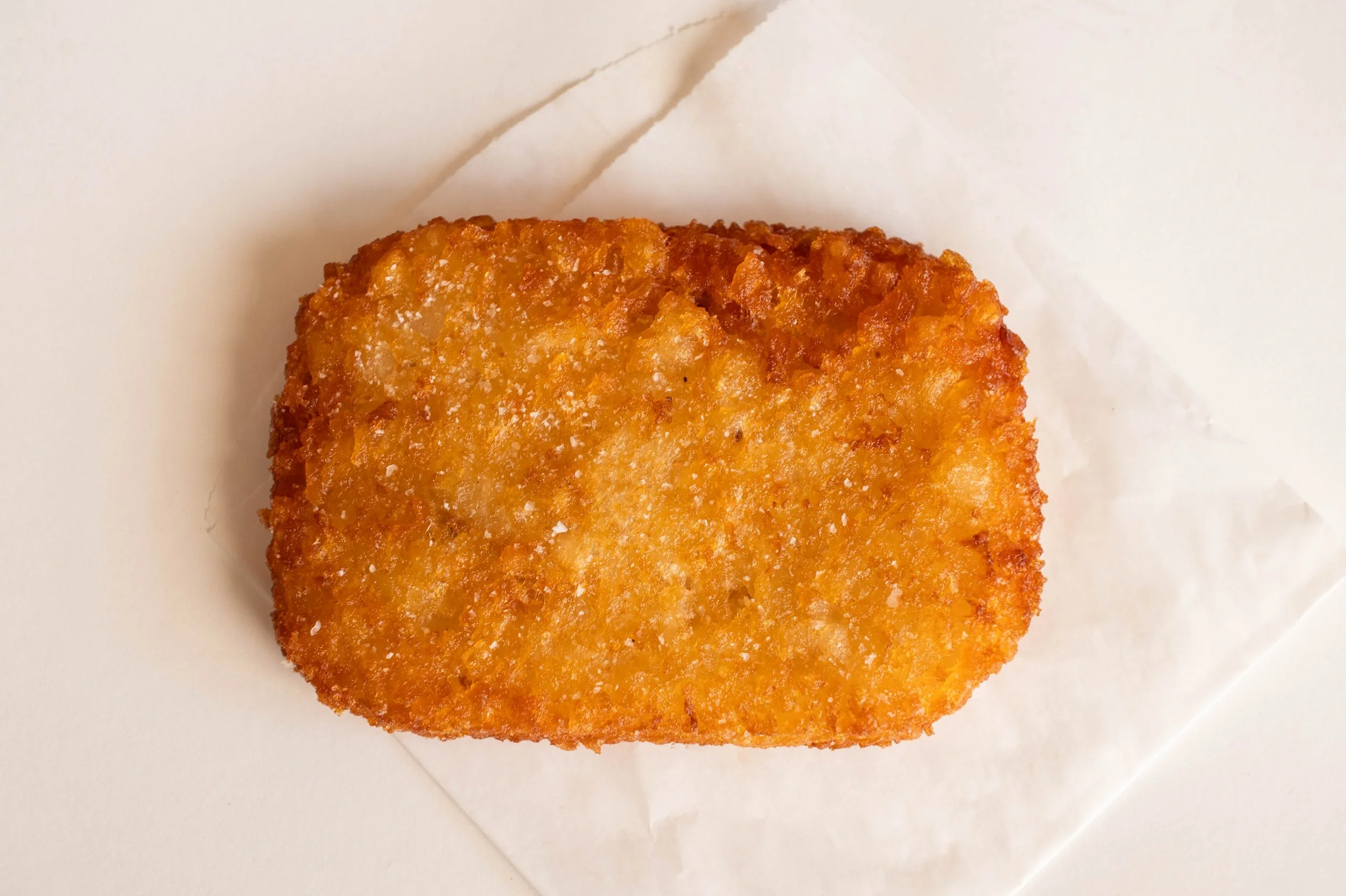 A fried hash brown potato patty on white paper.