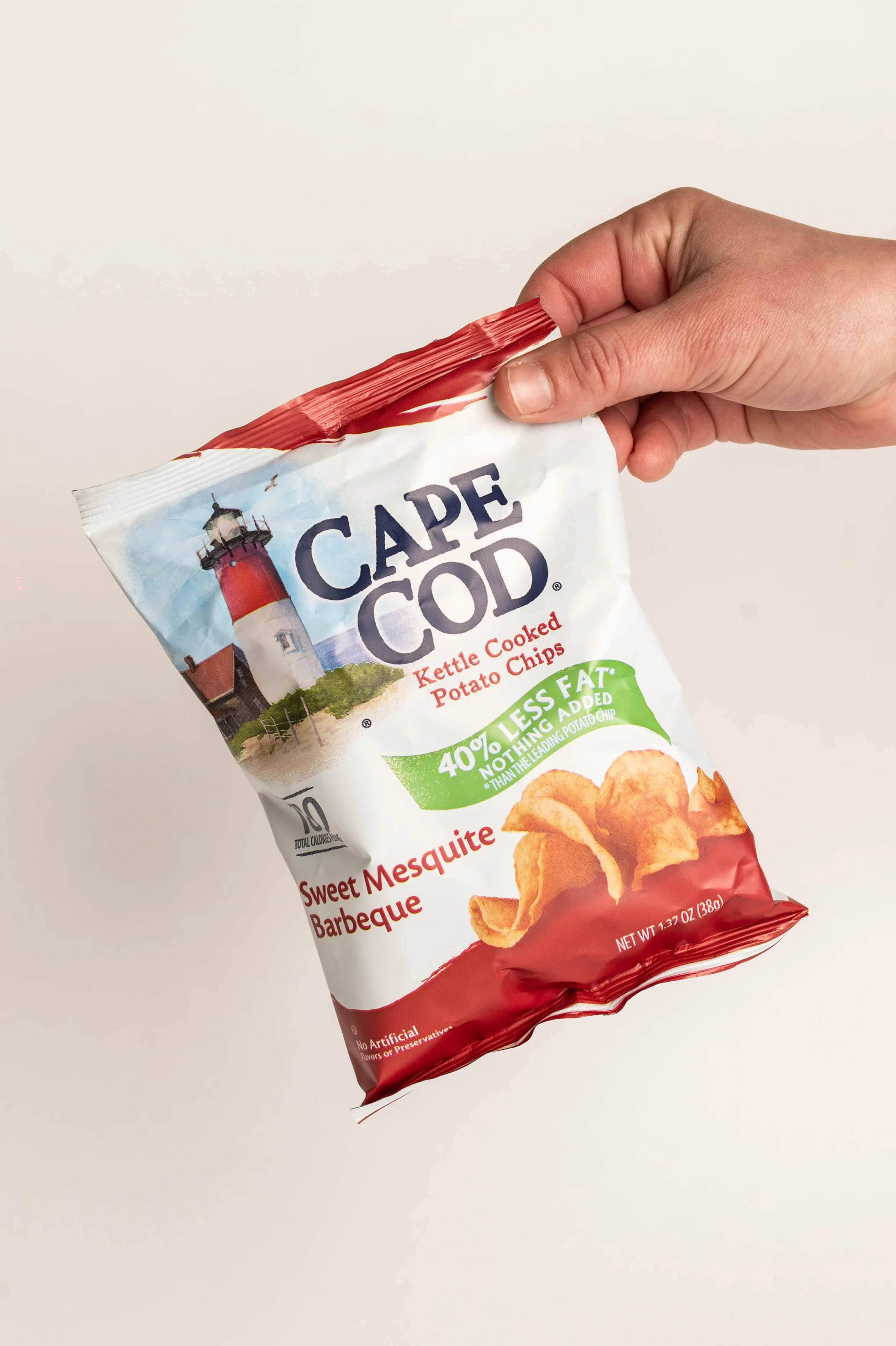 Hand holding a bag of Cape Cod Kettle Cooked Potato Chips, Sweet Mesquite Barbeque flavor.