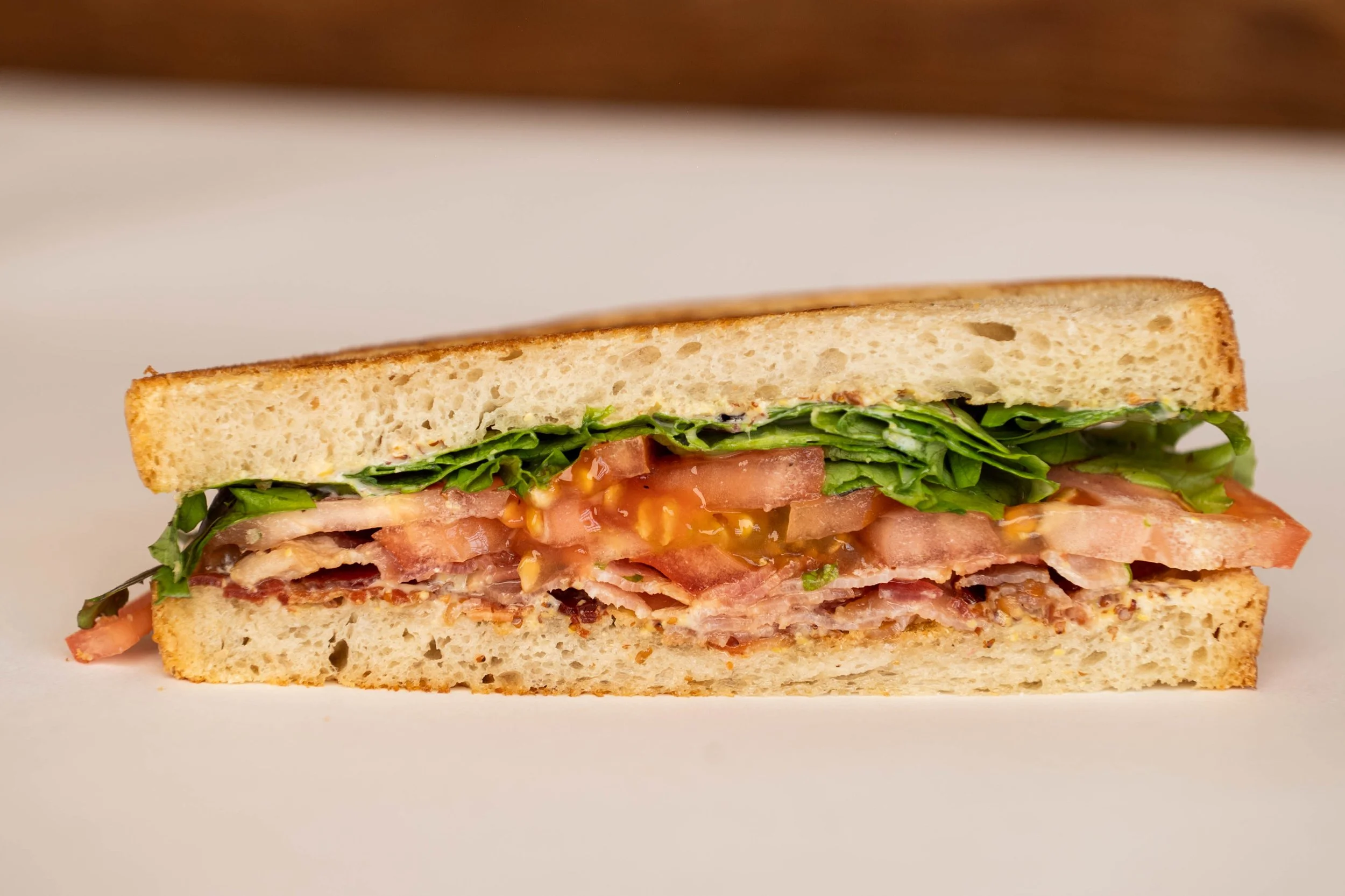 Club sandwich with lettuce, tomato, bacon, and mayonnaise on white bread.