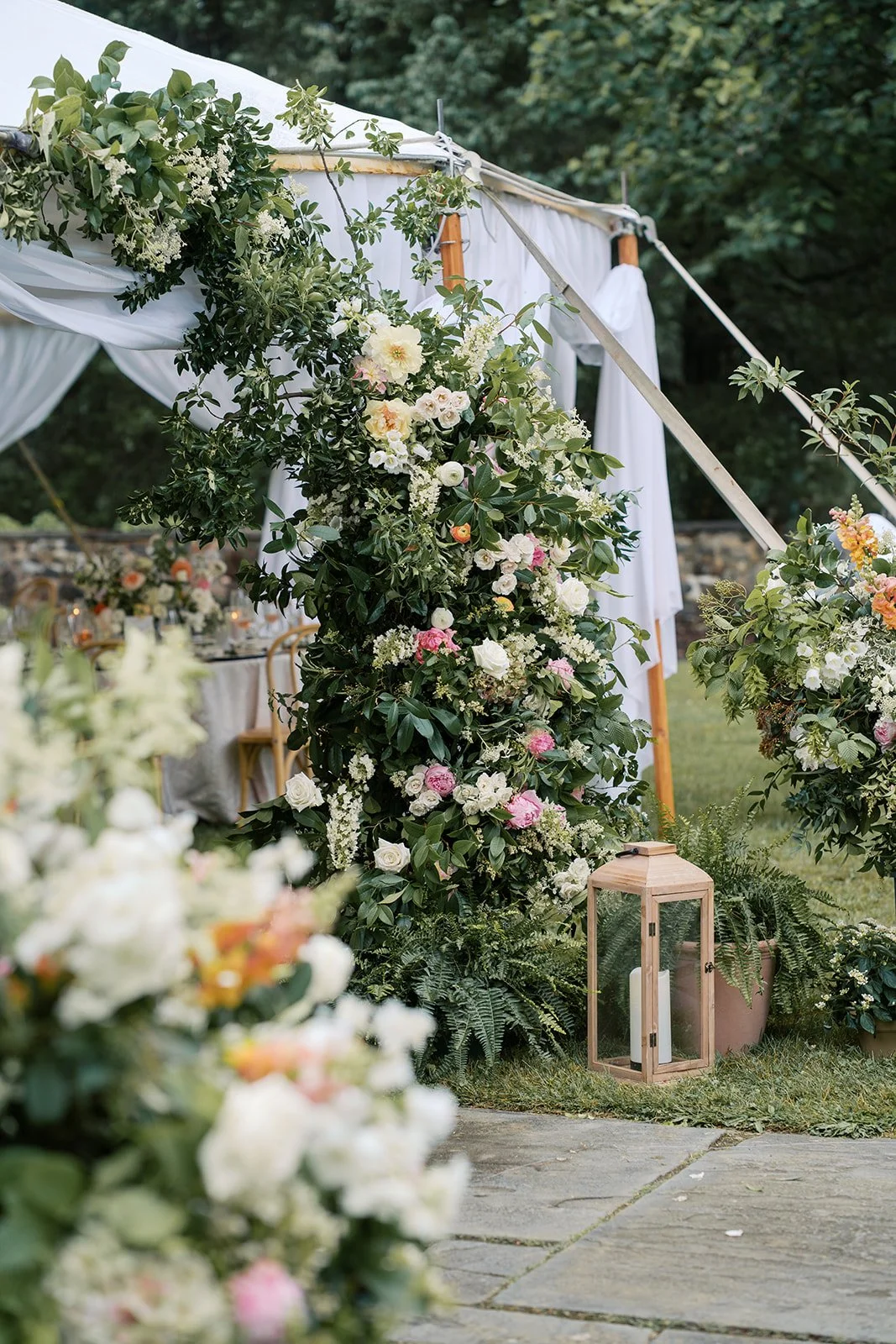 Decorative floral arch with pink and white flowers and green foliage at outdoor wedding ceremony site.