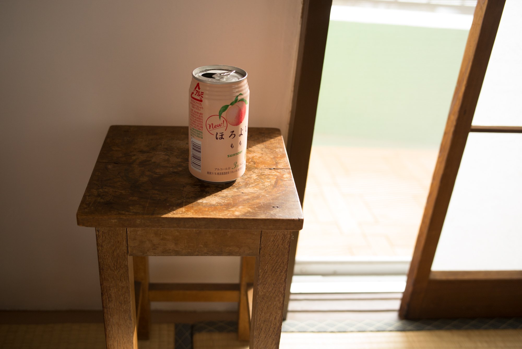Tokyo Japan. A can of peach-flavored beverage on a wooden table near a sliding door with sunlight streaming through.