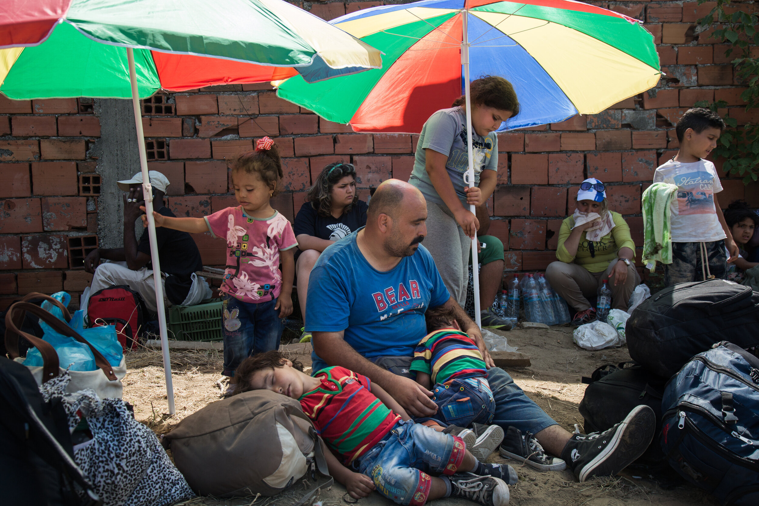  A refugee family waits at the reception center in Macedonia on August 26, 2015. After crossing from Greece into Macedonia, refugees are held at a reception center near the town of Gevgelija. To transit through Macedonia, they receive a document allo