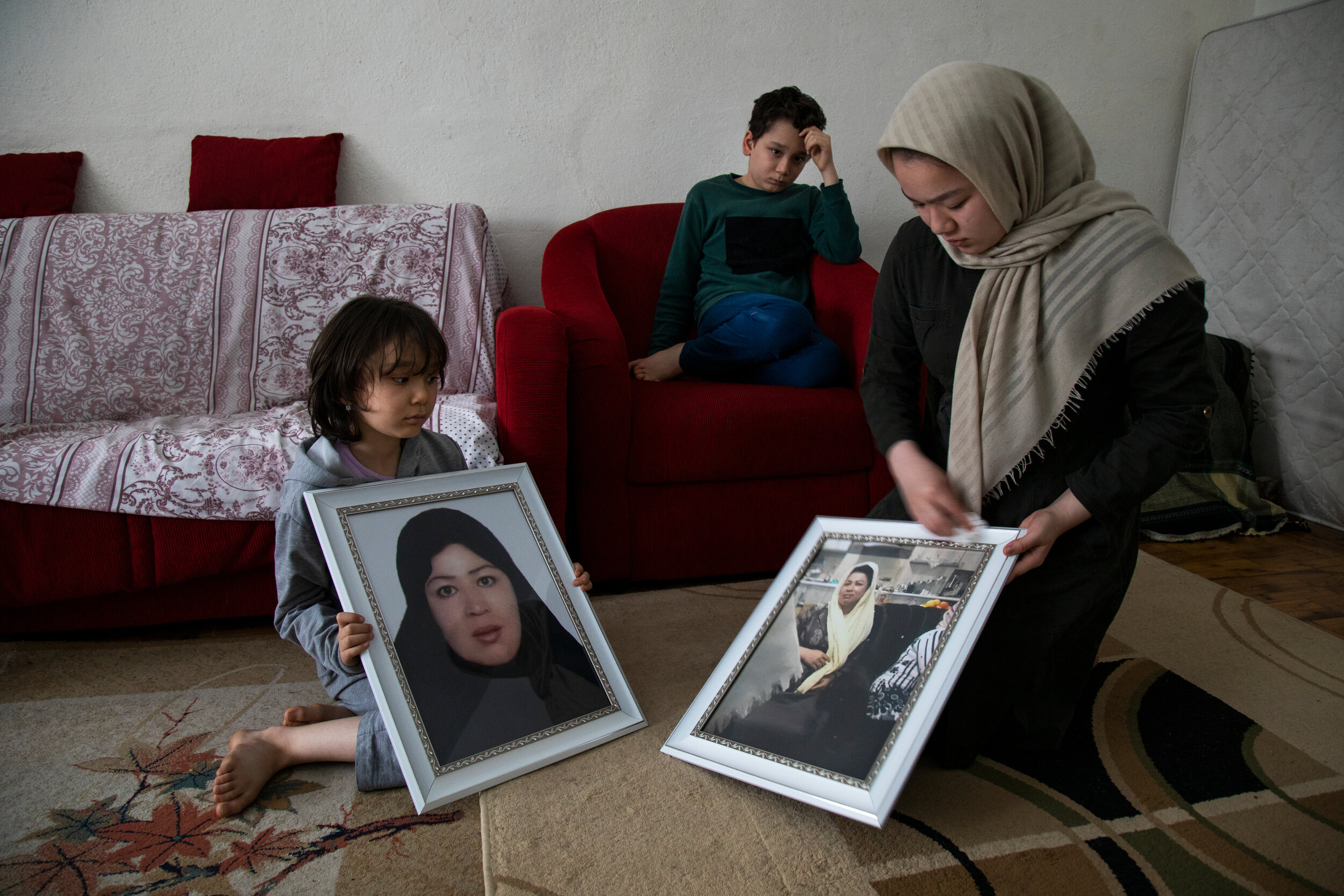  Afghan refugees Taiba, 7, Abdolhassan, 11, and Bahara, 14, clean photographs of her mother Roya.  They live with their father Muhammad in Turkey. While illegally crossing the Iran-Turkey border last year, they became separated from their mother. Her