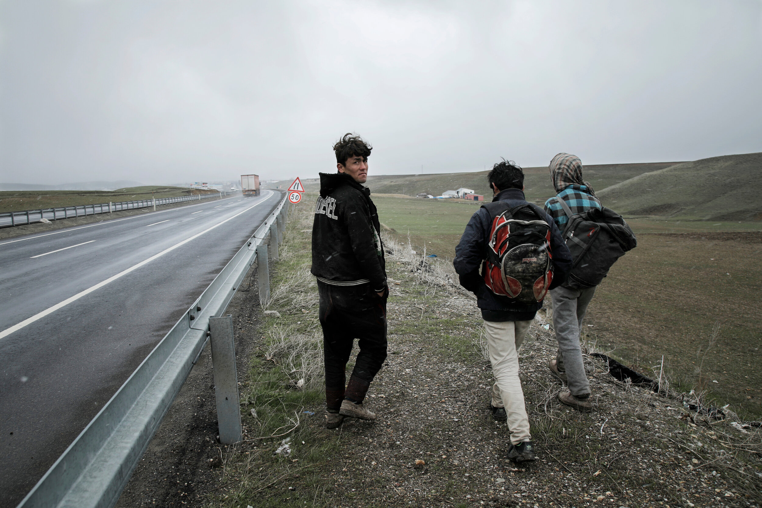  Afghan men walk along the highway between the Turkish cities of Dogubayazit and Agri, in eastern Turkey, near the border with Iran. After crossing the border illegally and unable to obtain proper documentation that would allow them to ride public tr