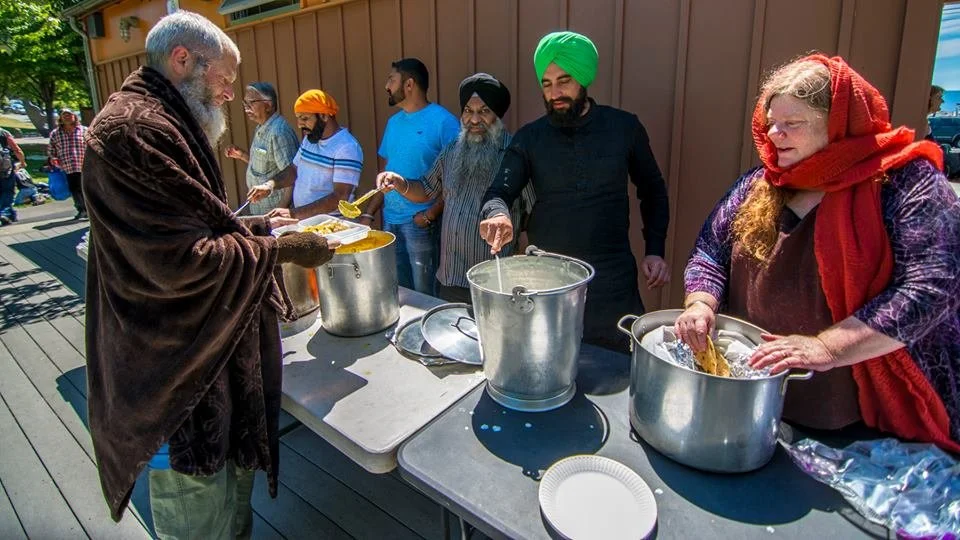 A group of people serve food to a man across the table from them.