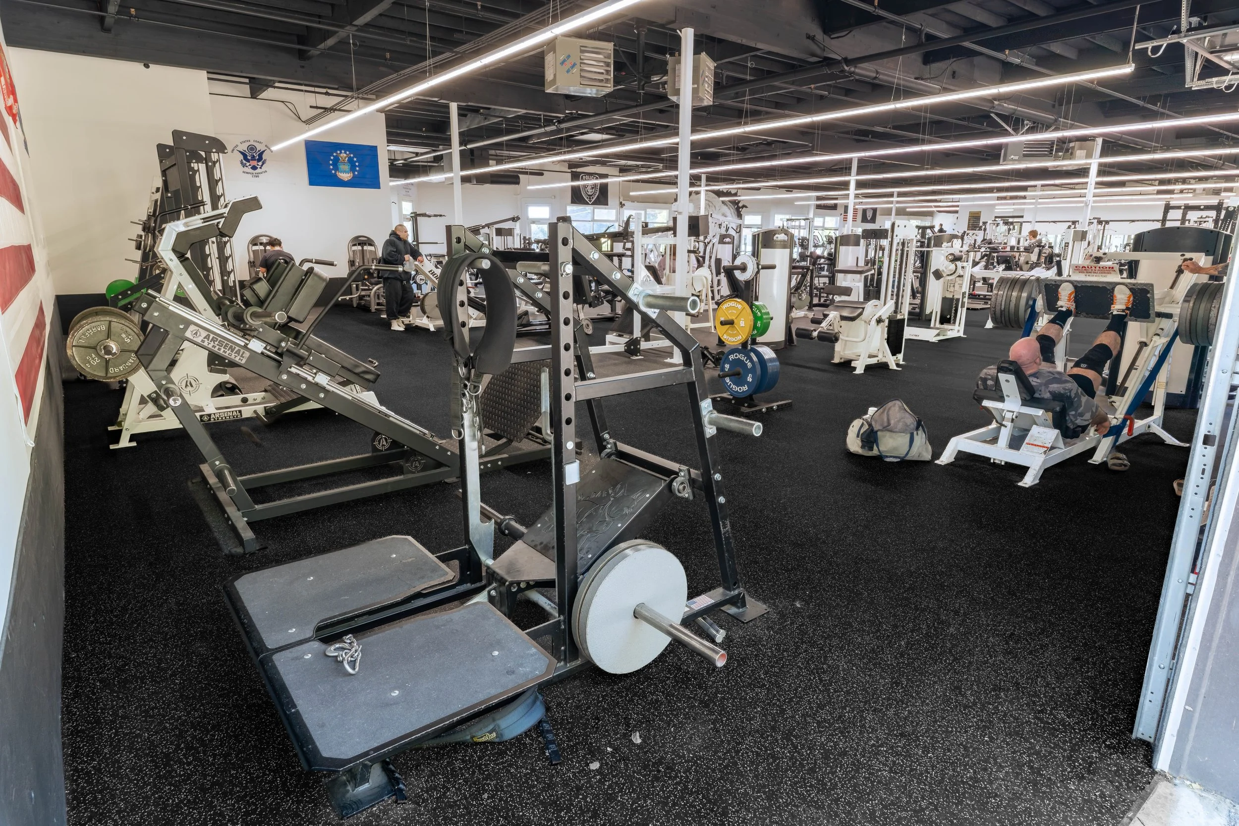 Strength training area at Southside Strength and Fitness featuring barbells, a standing chest press, and cable machines.