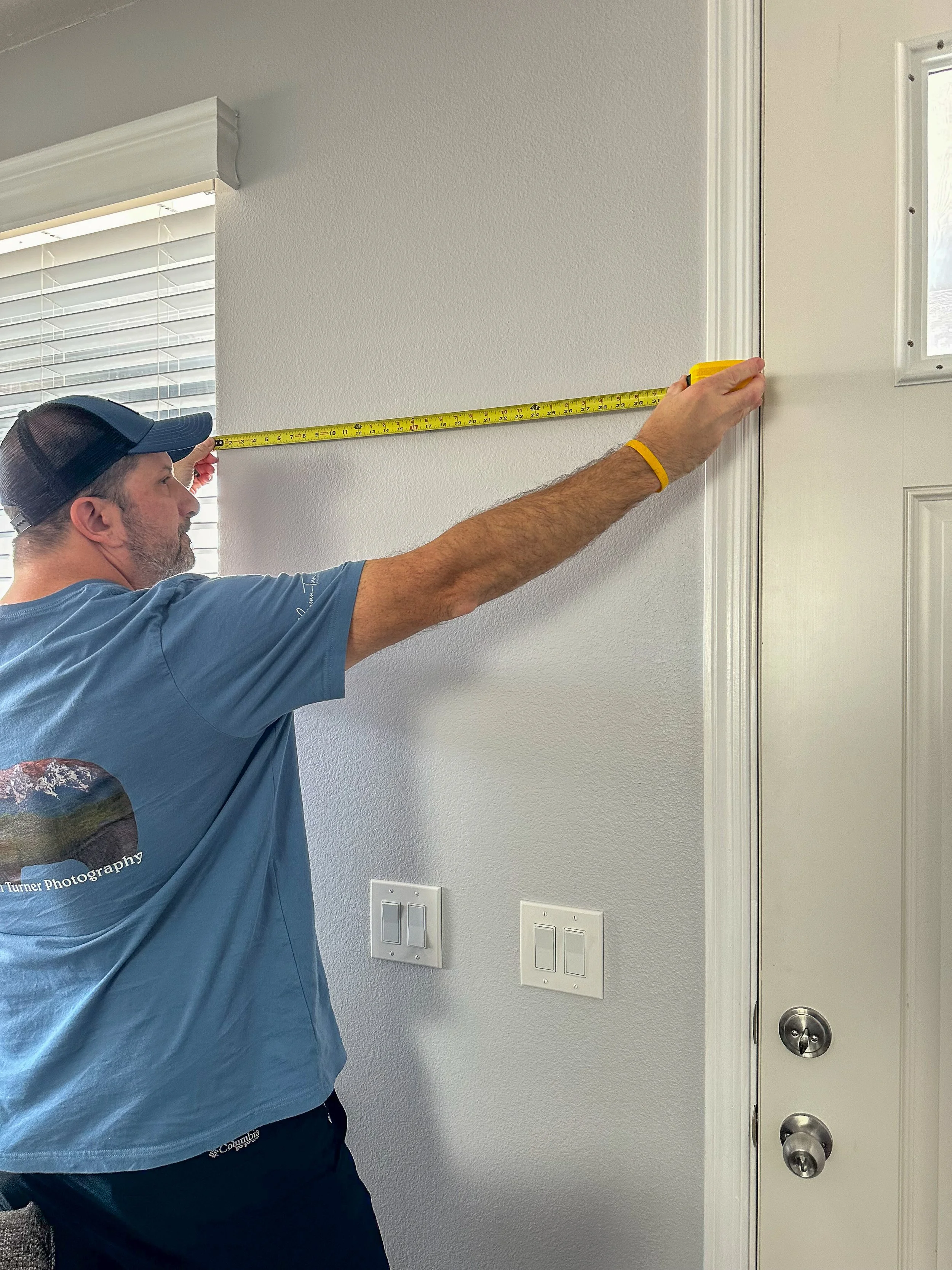 A man using a tape measure to measure a wall