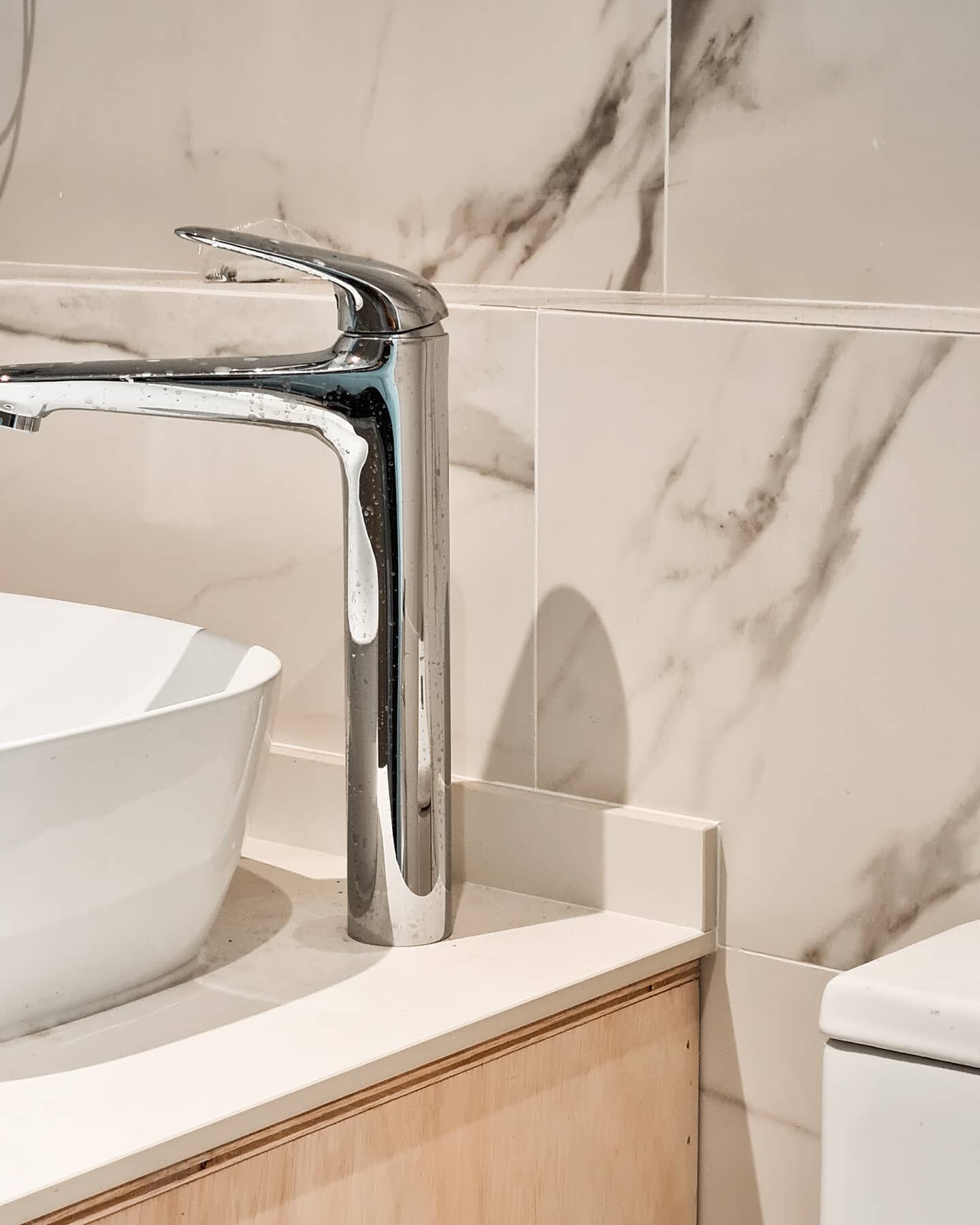 SWIPE ⏩ We are nearing another project completion and we're so psyched to share some snaps with all of you! This common bathroom wall is swathed in bright marble effect tiles. We also installed a simple glass shower screen and chrome fixtures to go a