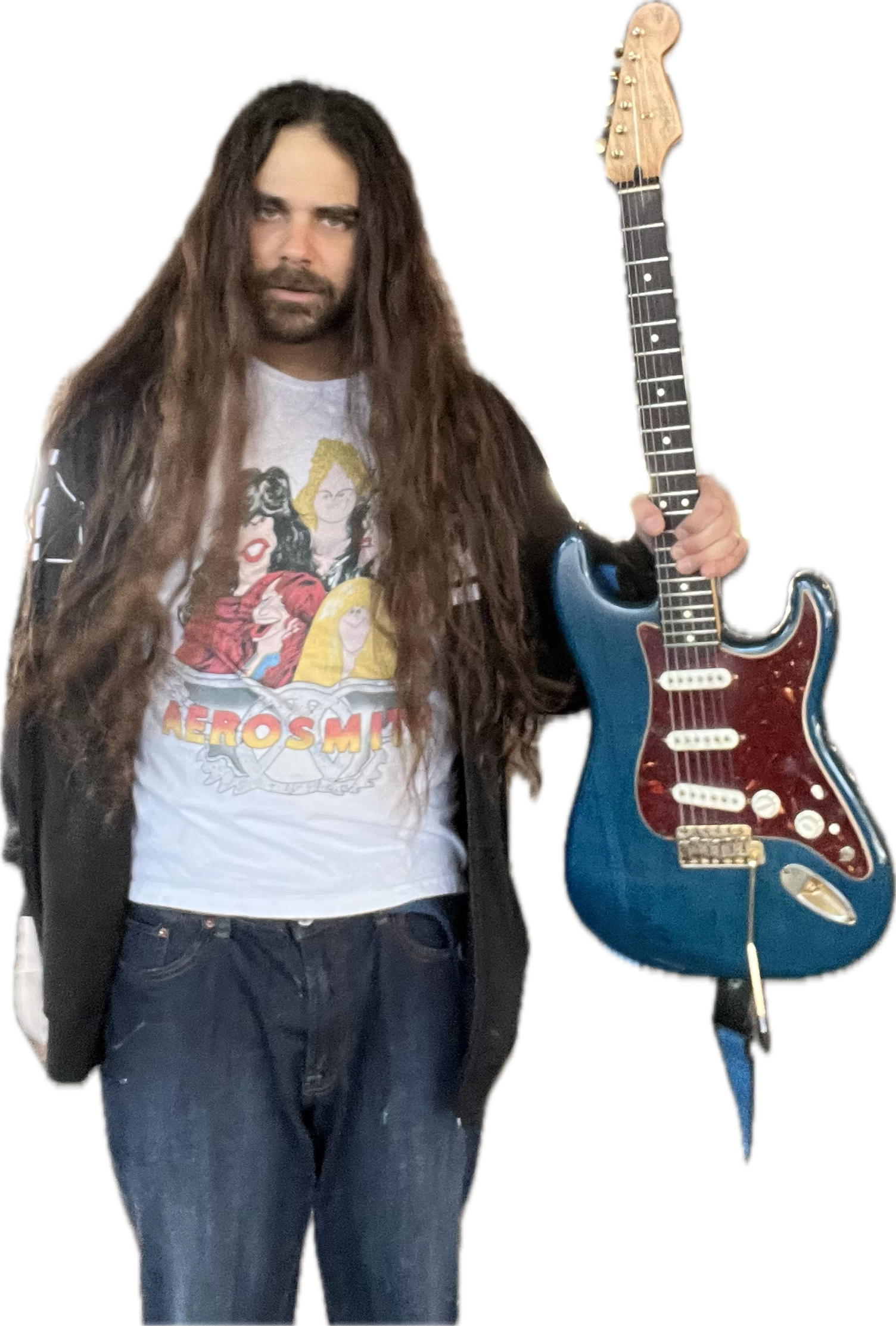 A man with long brown hair and a beard holding a blue and red electric guitar, wearing a white graphic T-shirt with 'Aerosmith' on it and black jeans, standing against a black background.