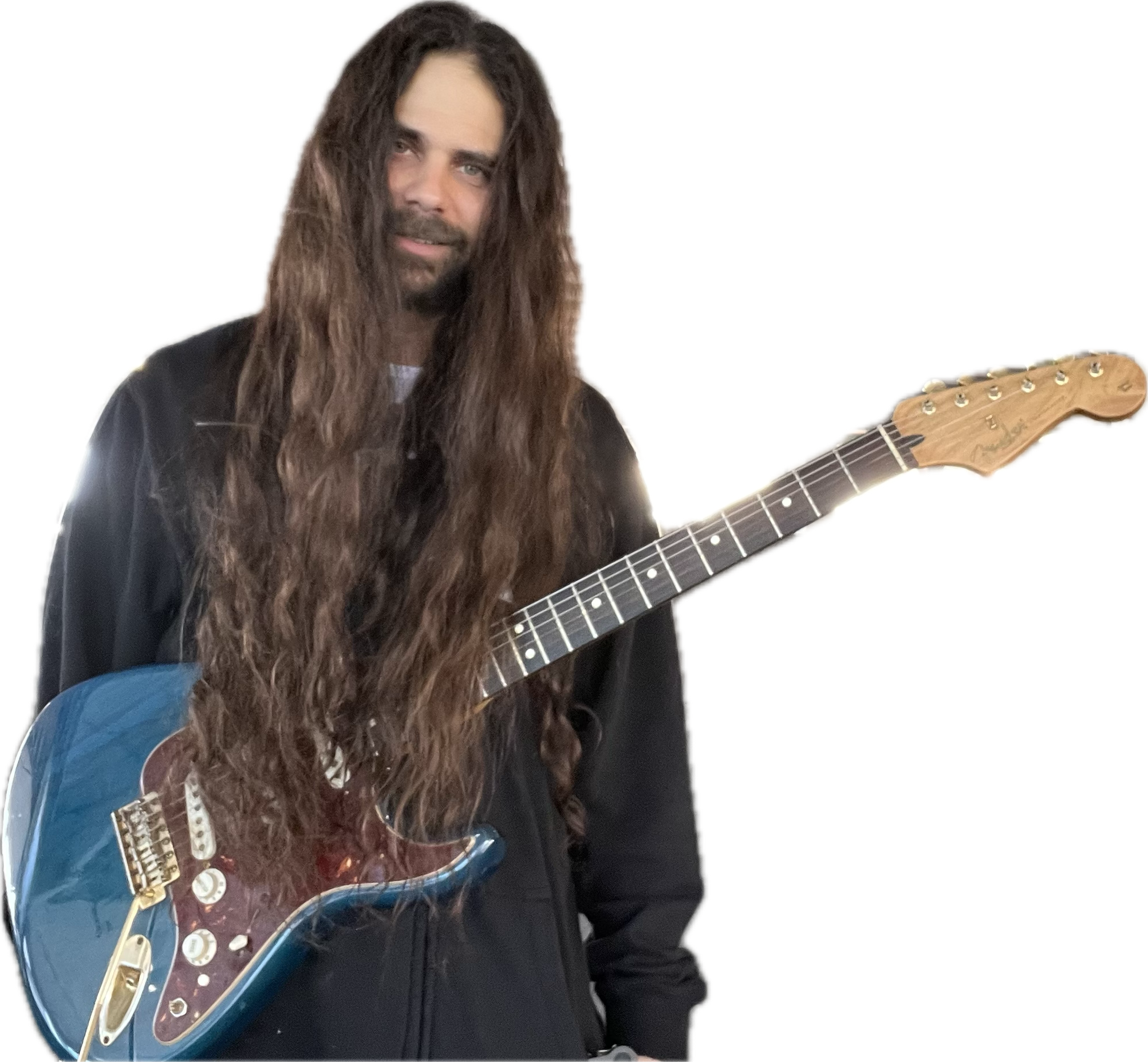 A man with long, wavy brown hair and a beard, holding a blue electric guitar, wearing a black jacket, standing against a black background.